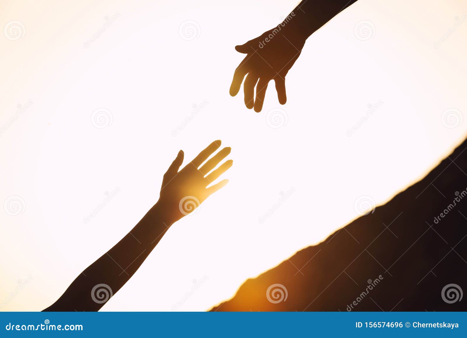 silhouettes of man and woman helping each other to climb on hill against sunset