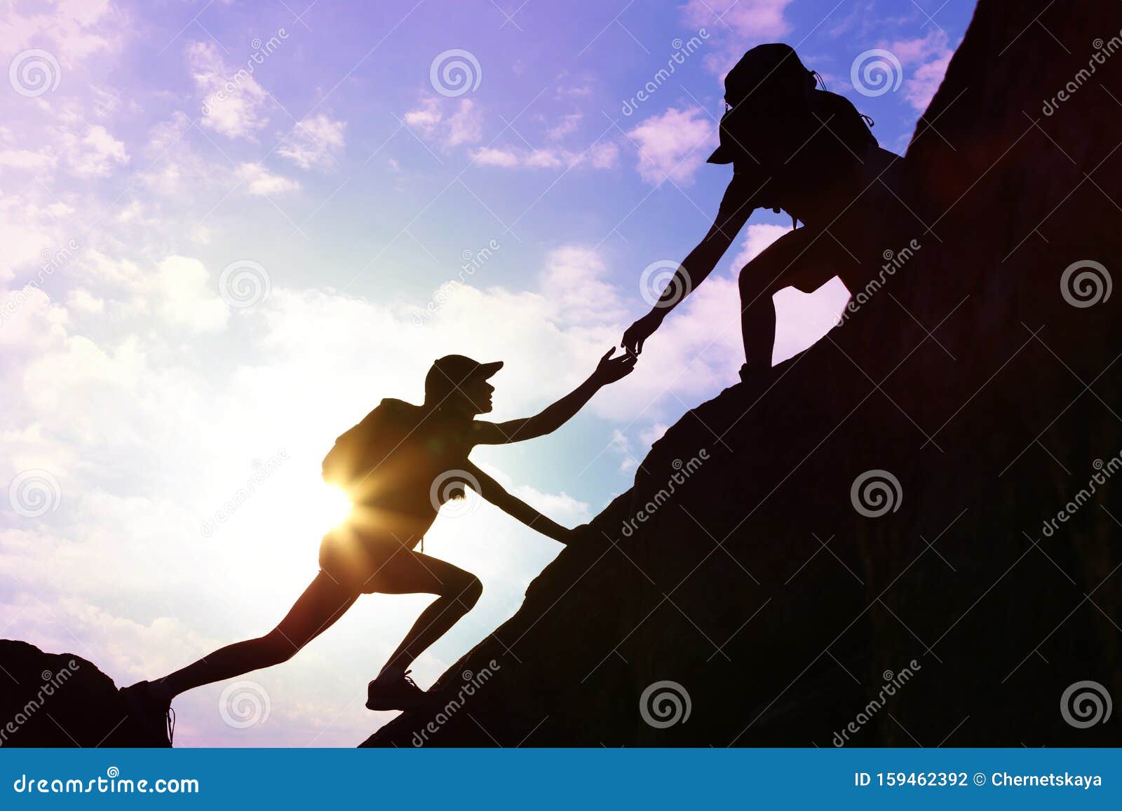 silhouettes of man and woman helping each other to climb on hill