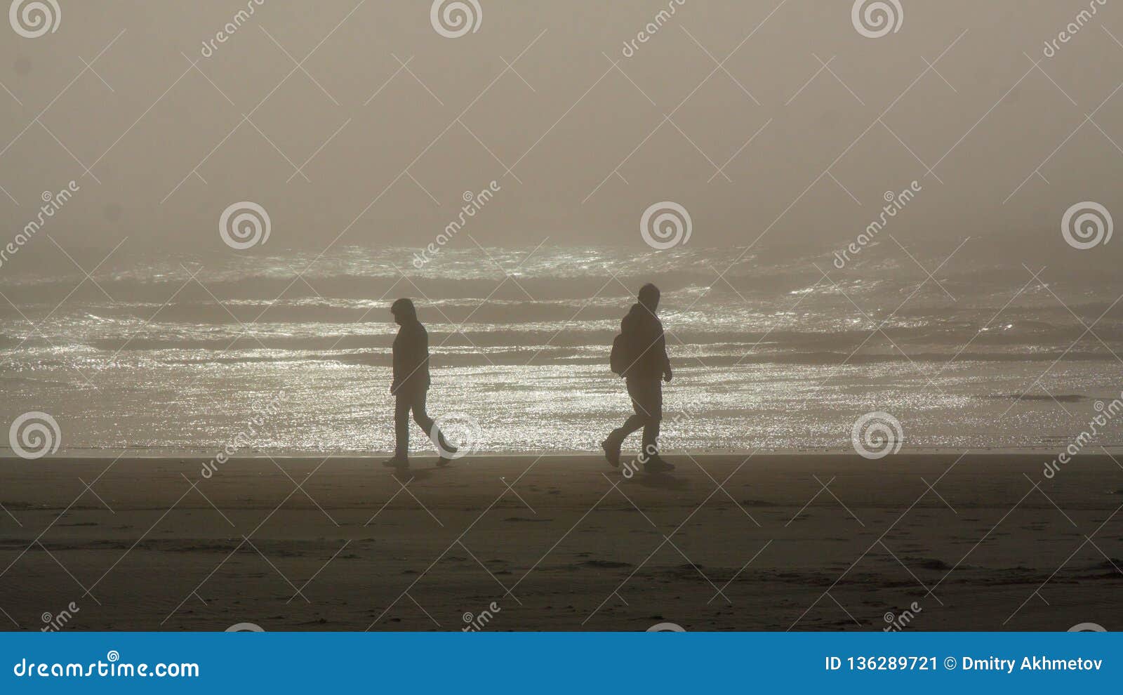 silhouettes of two persons walking in an opposite directions on a tillamook beach, oregon