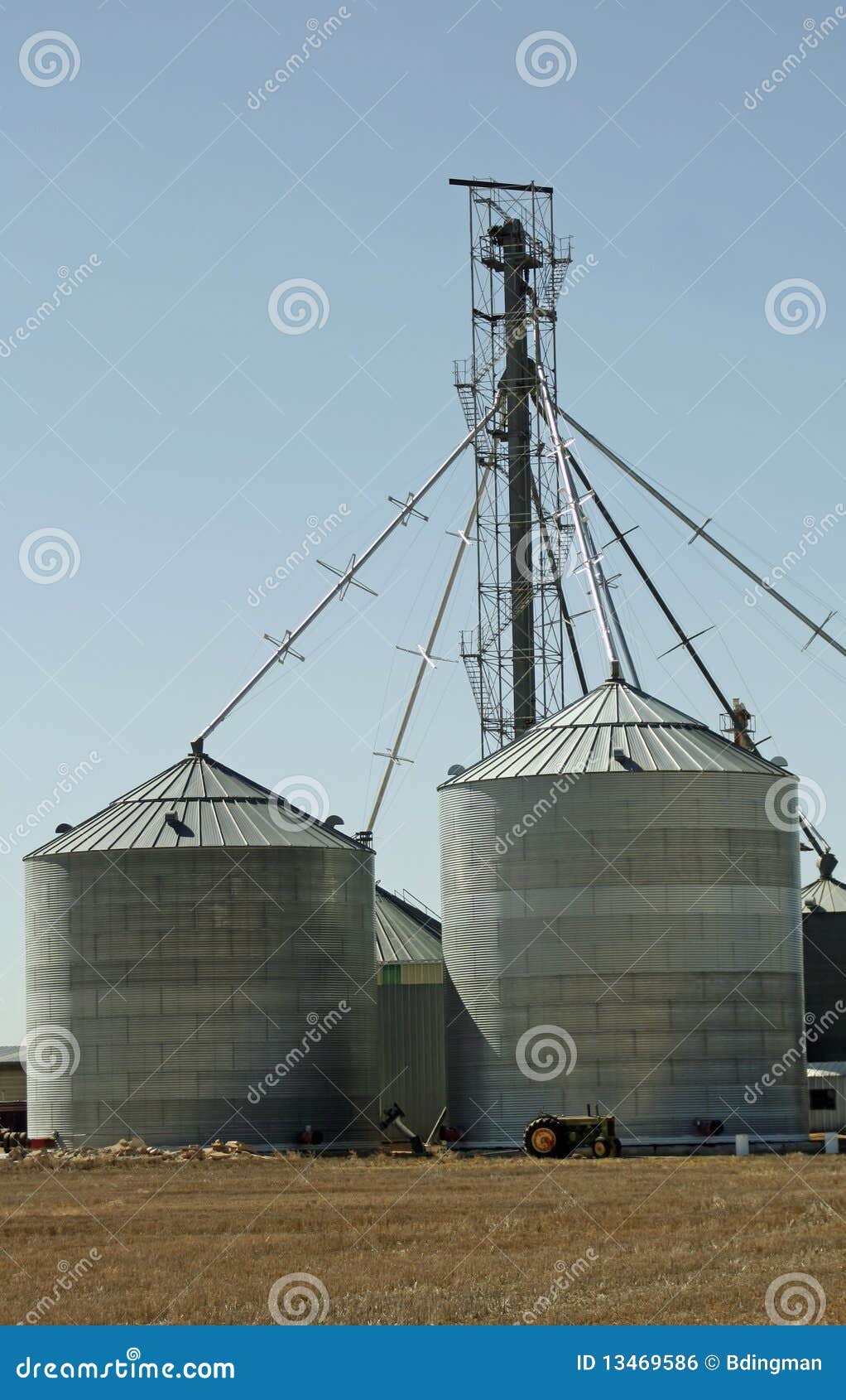 Sili dell'azienda agricola. Un trattore si leva in piedi davanti ai sili di granulo su un'azienda agricola del Colorado. I sili possono essere usati per i tipi differenti di granuli e di cereali.