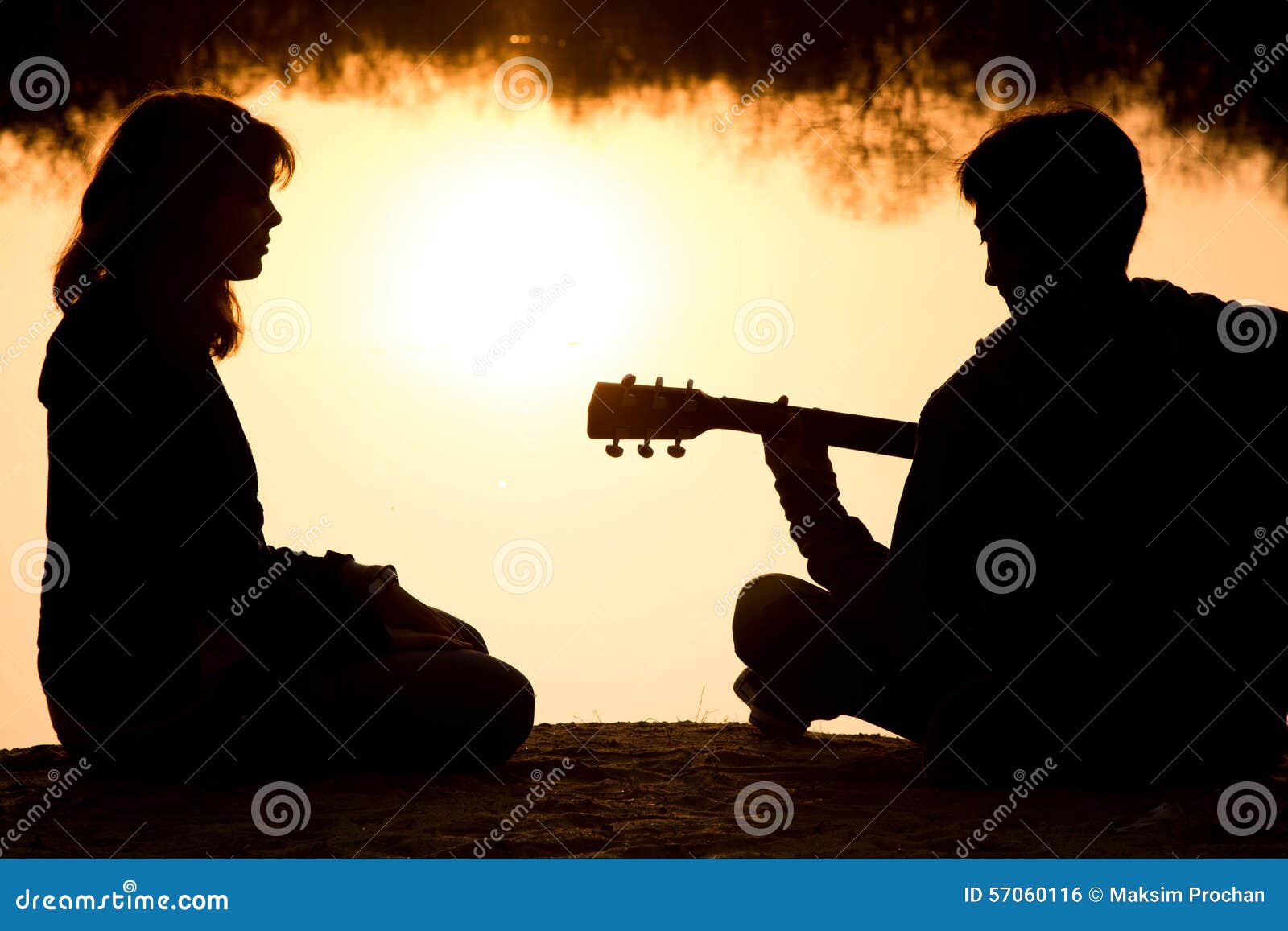 Silueta de un muchacho y de una muchacha jovenes en la playa con una guitarra