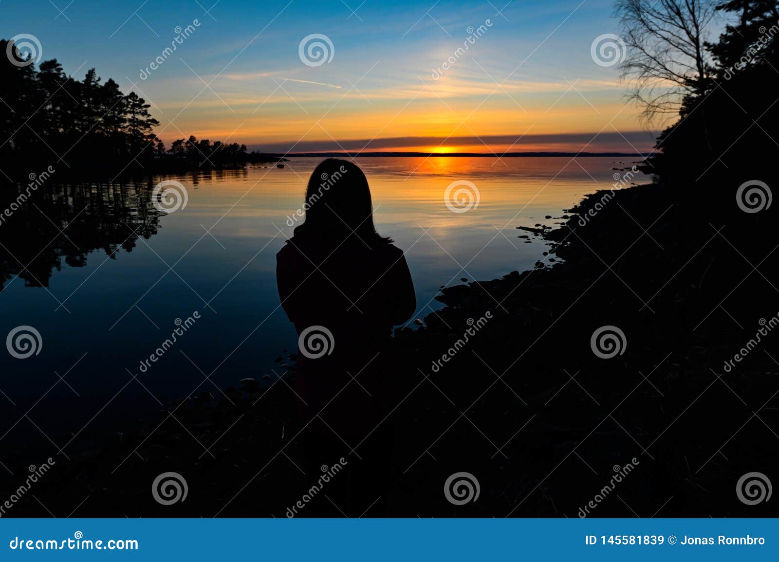 siluette of a young person standing infront of a sunset