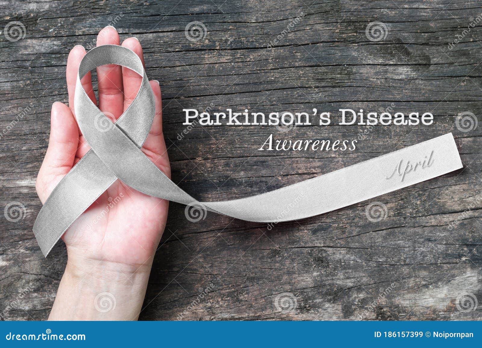 silver color ribbon on hand support  with clipping path for parkinson`s disease awareness and brain cancer tumor illness