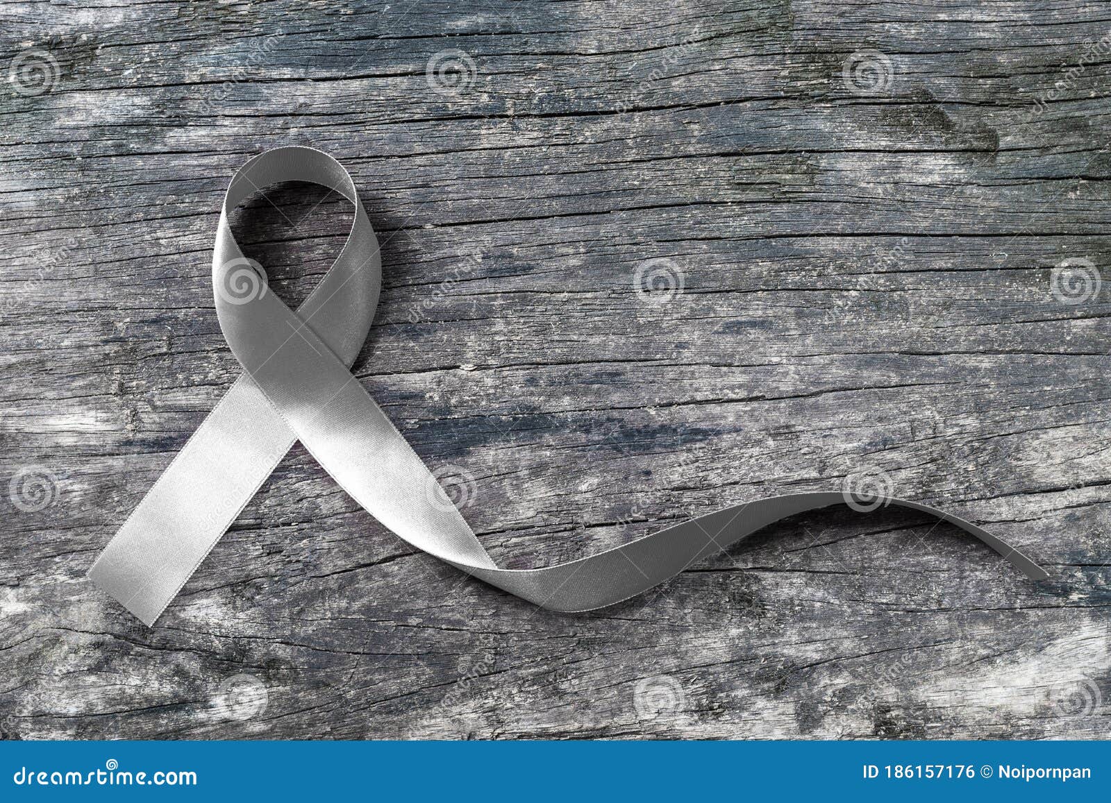 silver color ribbon on old aged wood  with clipping path for parkinson`s disease awareness and brain cancer tumor