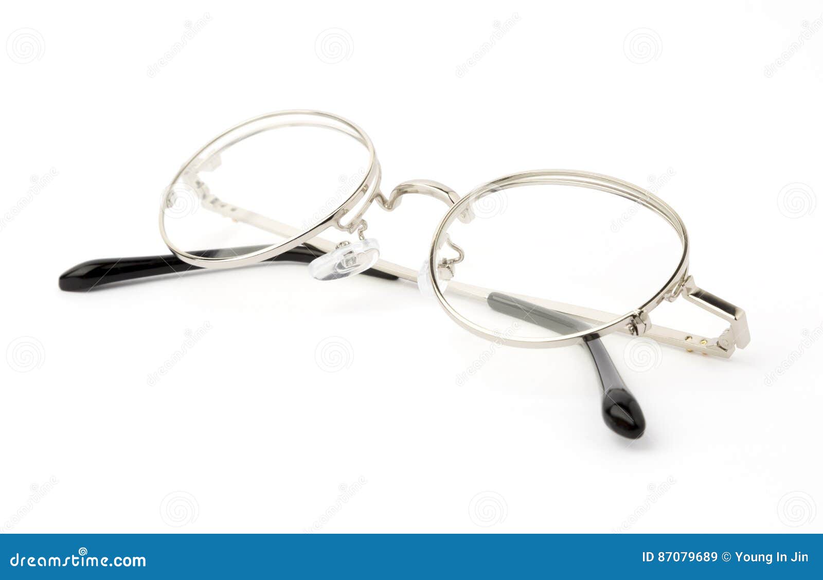 Glasses With Folded Arches Lie On A Yellow Surface. Above Lies A Lens