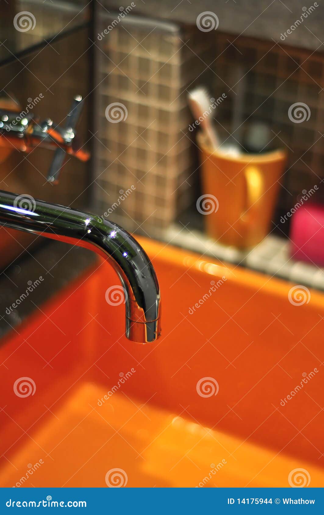 silver tap with orange basin and toiletries