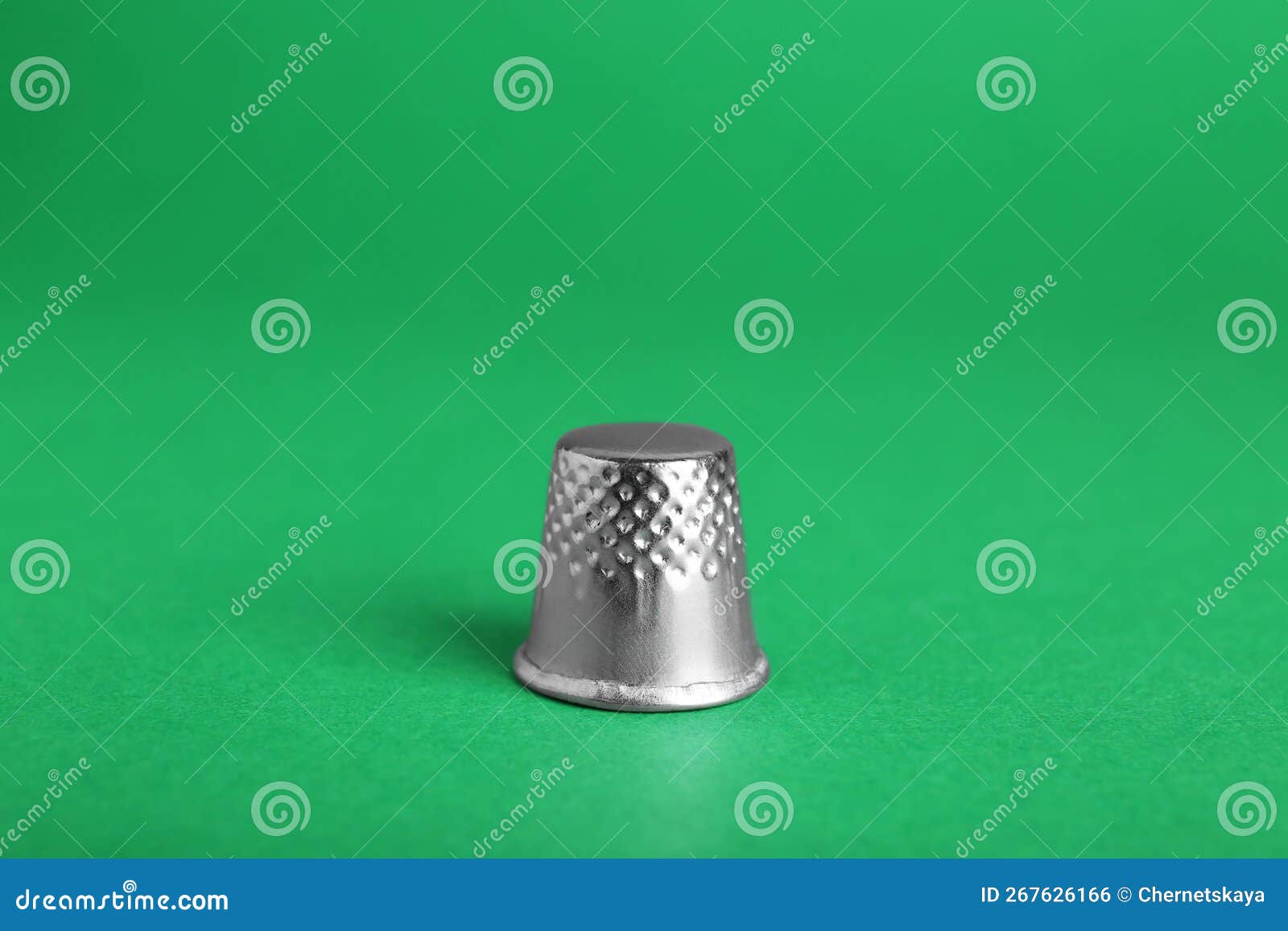 Silver Thimble on Green Background. Sewing Accessory Stock Photo
