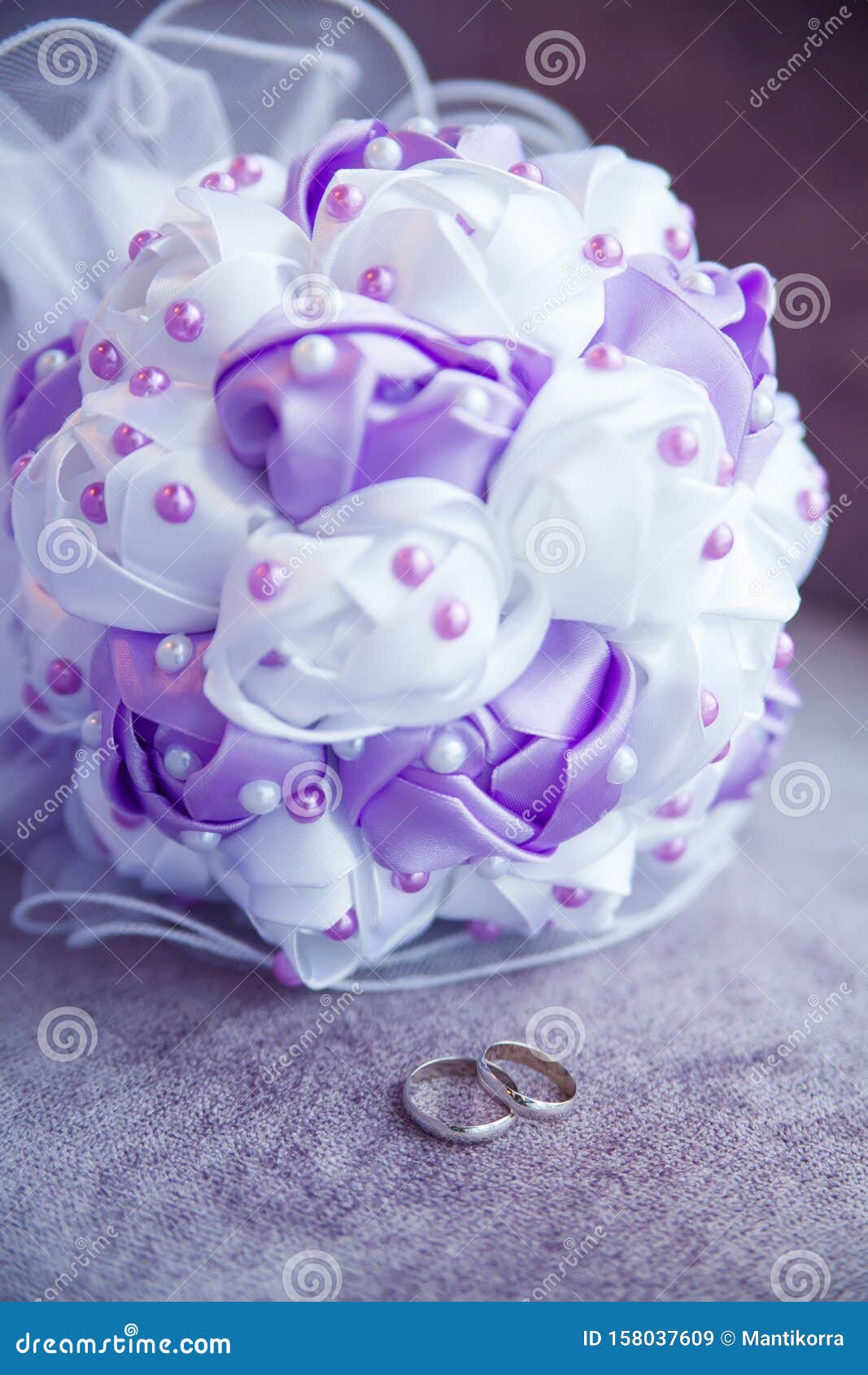 Với nhẫn cưới bạc và bó hoa cưới được bố trí trên nền tím, hình ảnh này chắc chắn sẽ làm say đắm các cặp đôi đang chuẩn bị cho ngày trọng đại của mình. Đường nét tinh tế và màu sắc hài hoà, tạo nên một thiết kế thiên về vẻ đẹp sang trọng, tinh tế.