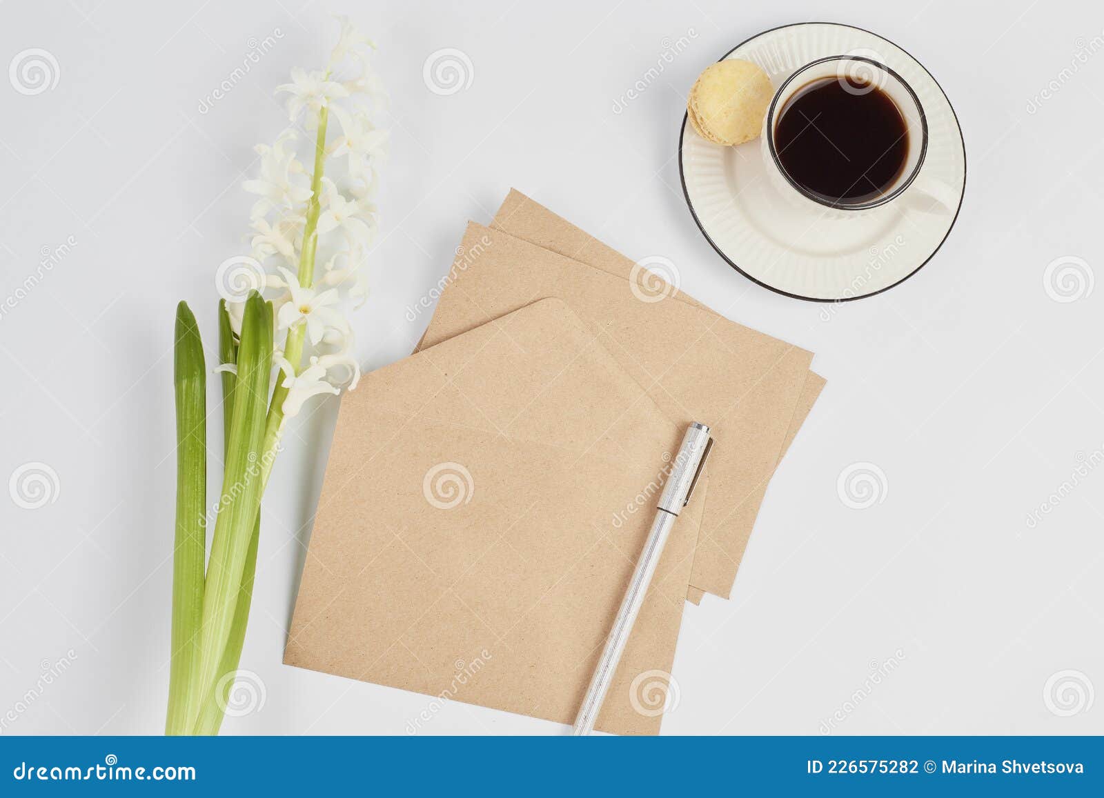 simple arrangement of a hyacinth flower, a cup of coffee and craft envelopes. minimalistic workplace. invitation cards for wedding