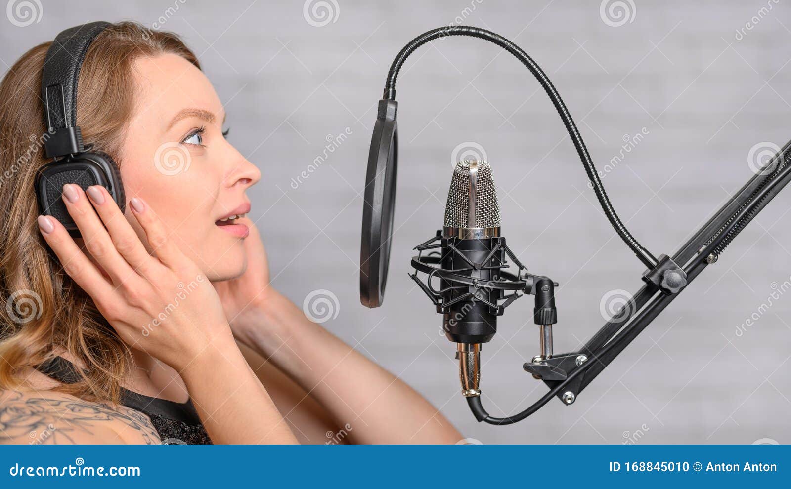 singer with a tattoo sings rock music in the studio into a microphone, musician and treble vocals