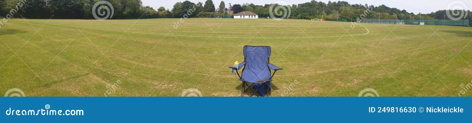 single beach chair in an empty playing field on a summers day