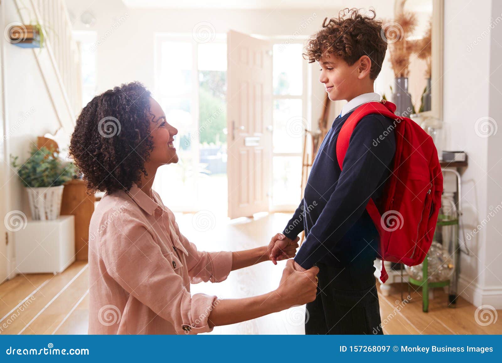 single mother at home getting son wearing uniform ready for first day of school