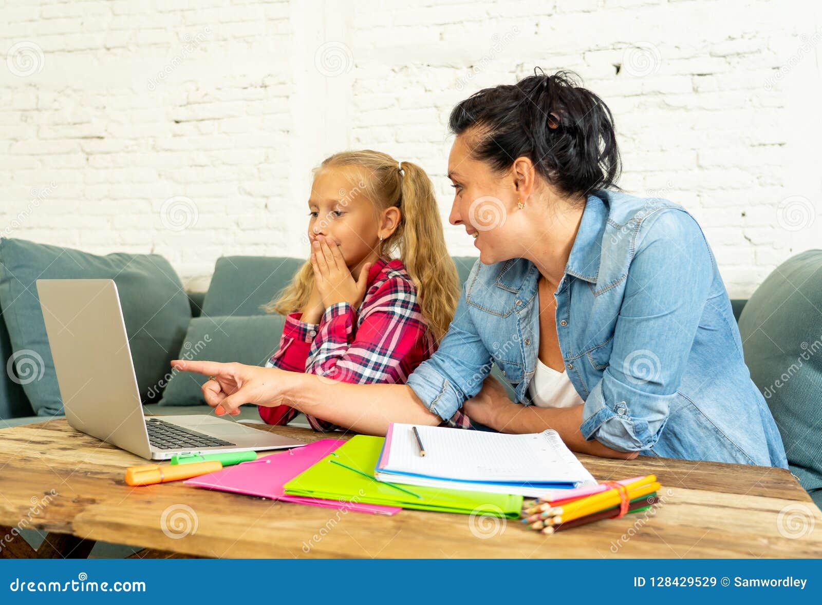 Single Mum Helping Her Daughter Doing Her Homework With Laptop At Home 