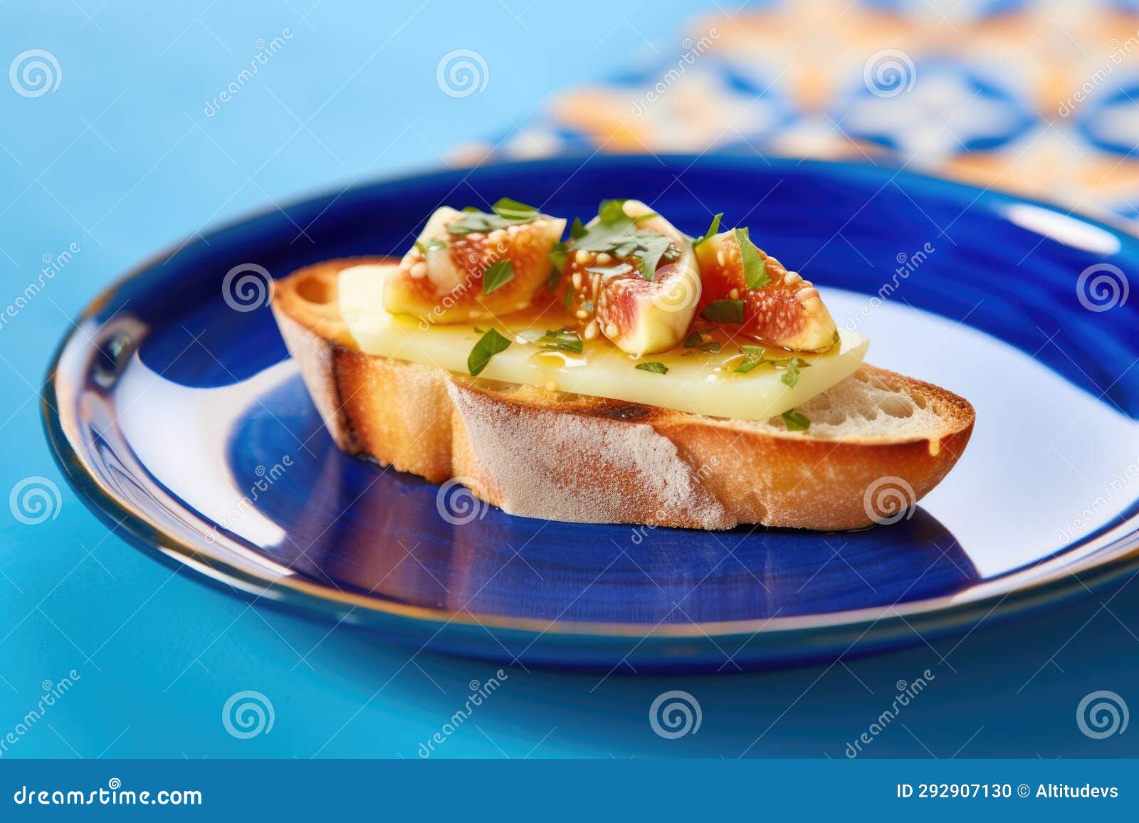 A Single Piece of Fig and Cheese Bruschetta on a Bright Blue Plate