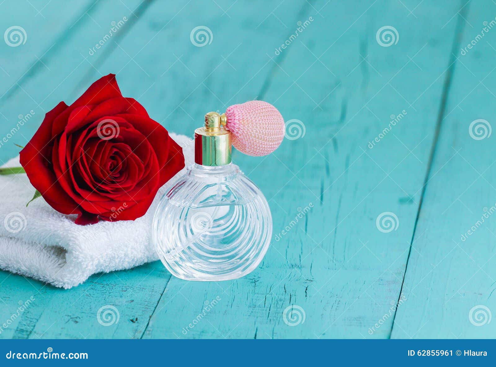 Single Red Rose and Perfume Bottle on Teal Blue Wood Background Stock