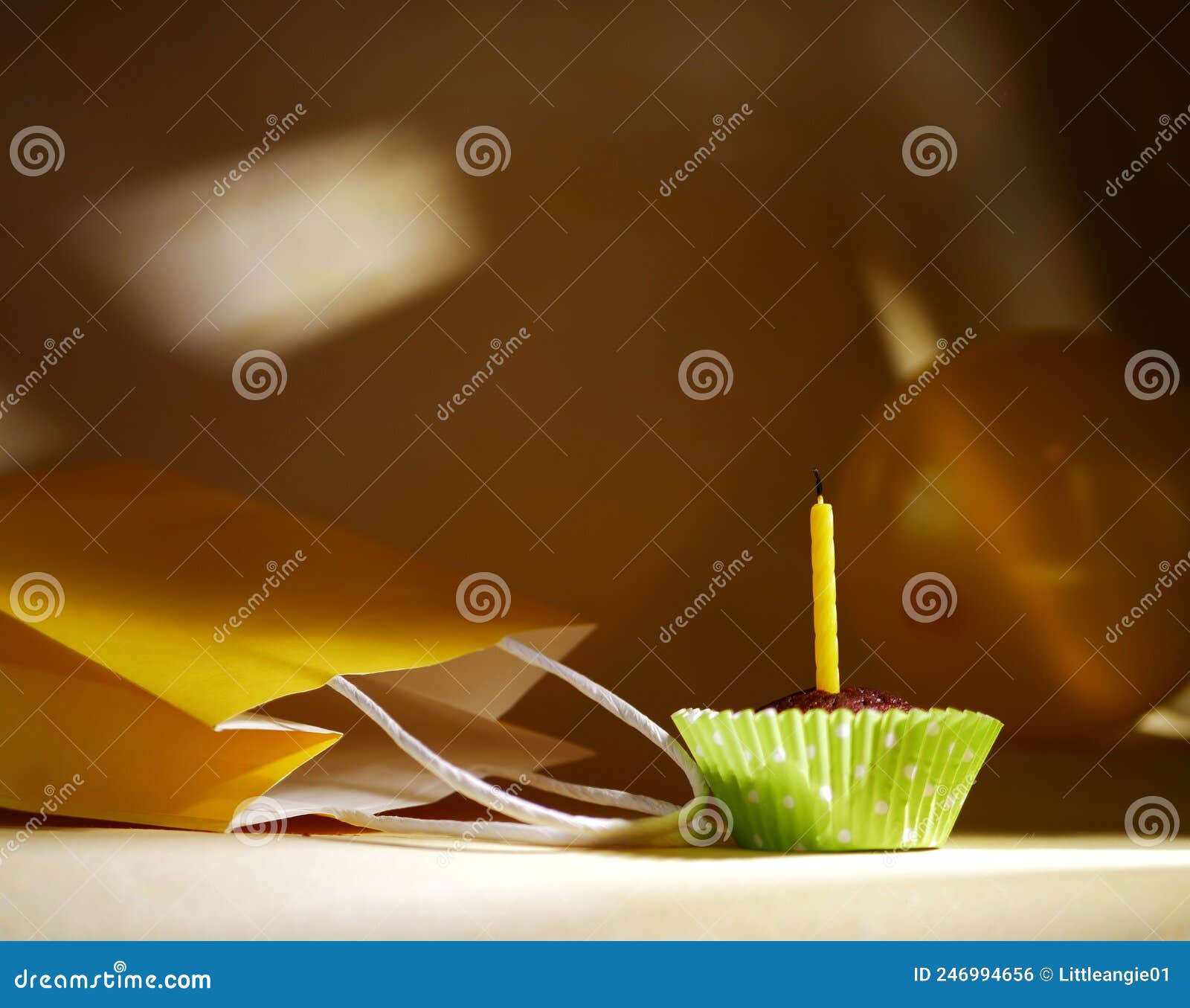 Single Yellow Birthday Candle on Cupcake with Gift Bag Stock Photo