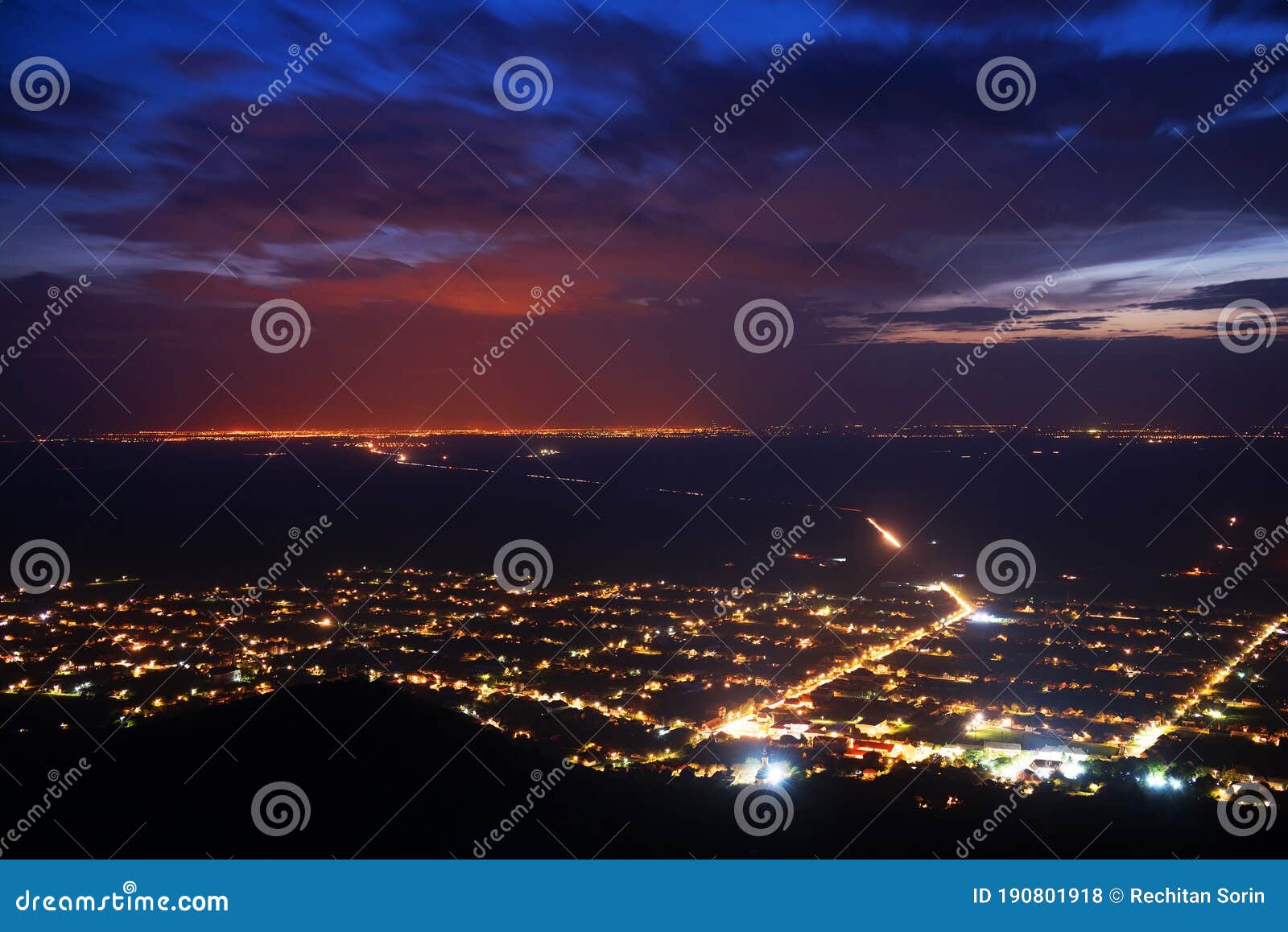 siria village seen from the siria fortress at night. the bright lights of the city arad in the background.