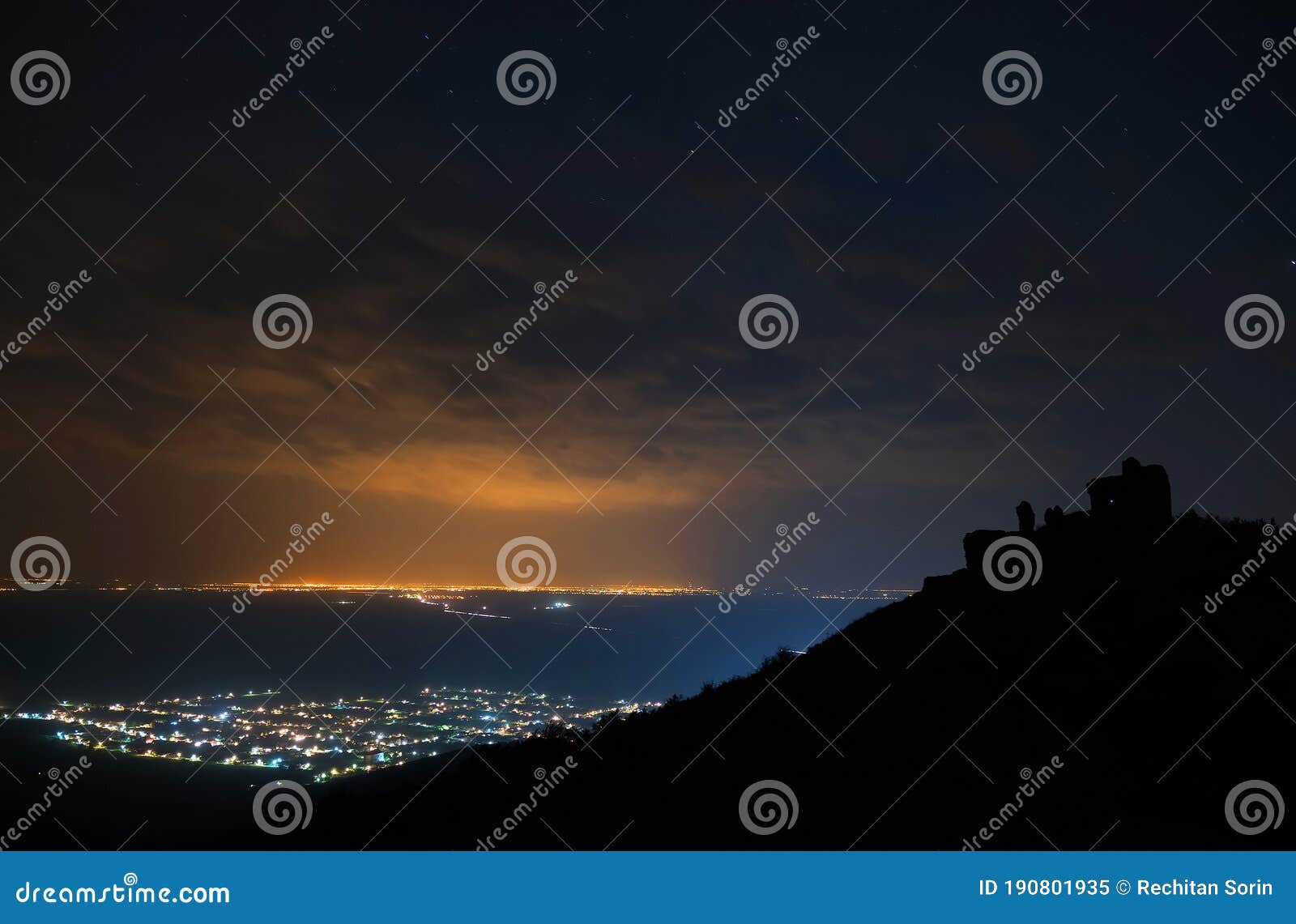 siria village seen from the siria fortress at night. the bright lights of the city arad in the background.