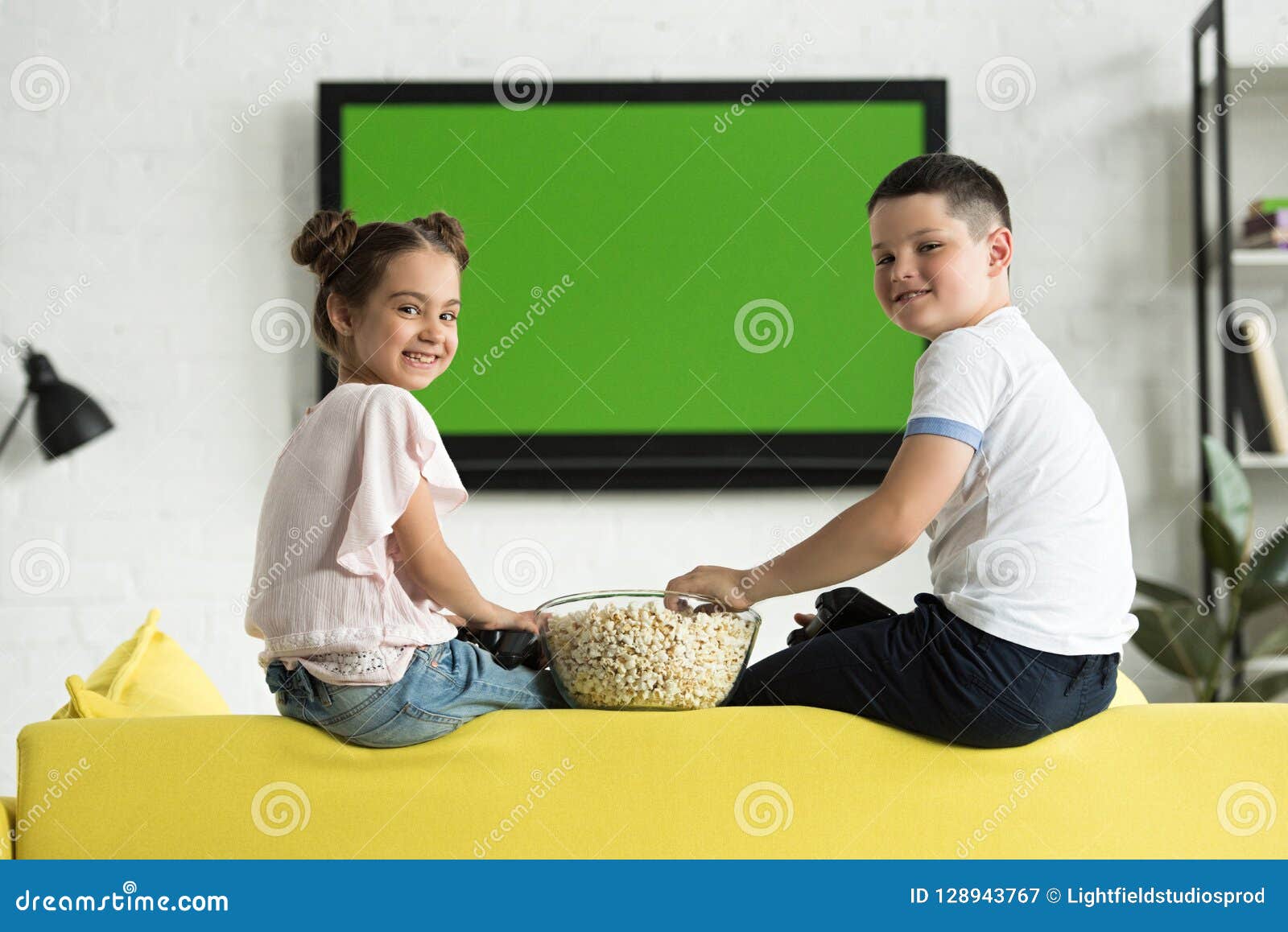 Sister and Brother Eating Popcorn at Home and Looking Stock Image