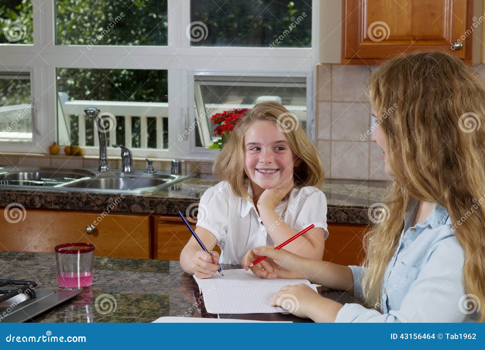 Sisters Doing Their Homework while in the Kitchen Stock Photo Image