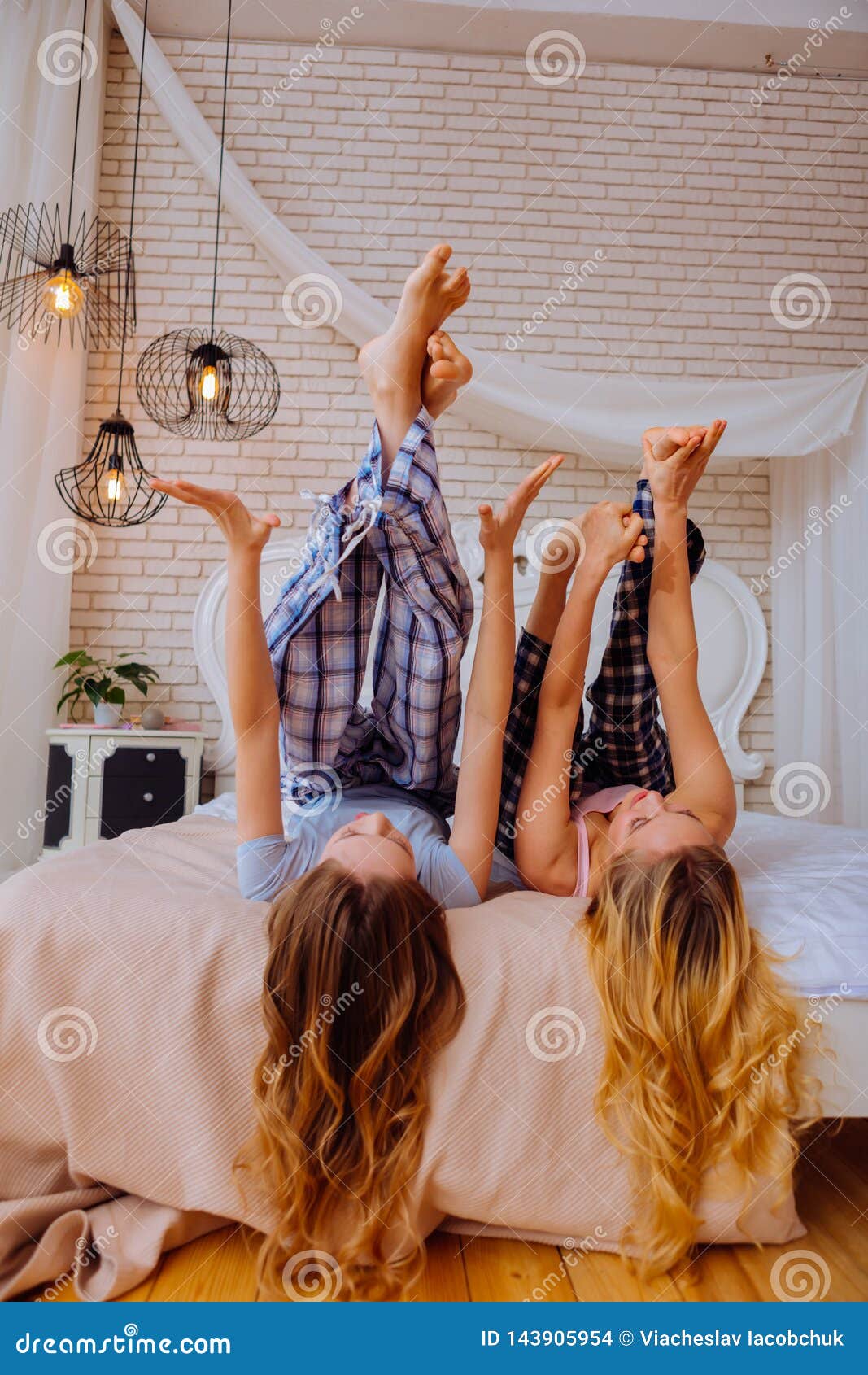 Sisters With Long Blonde Hair Raising Their Legs While Stretching In