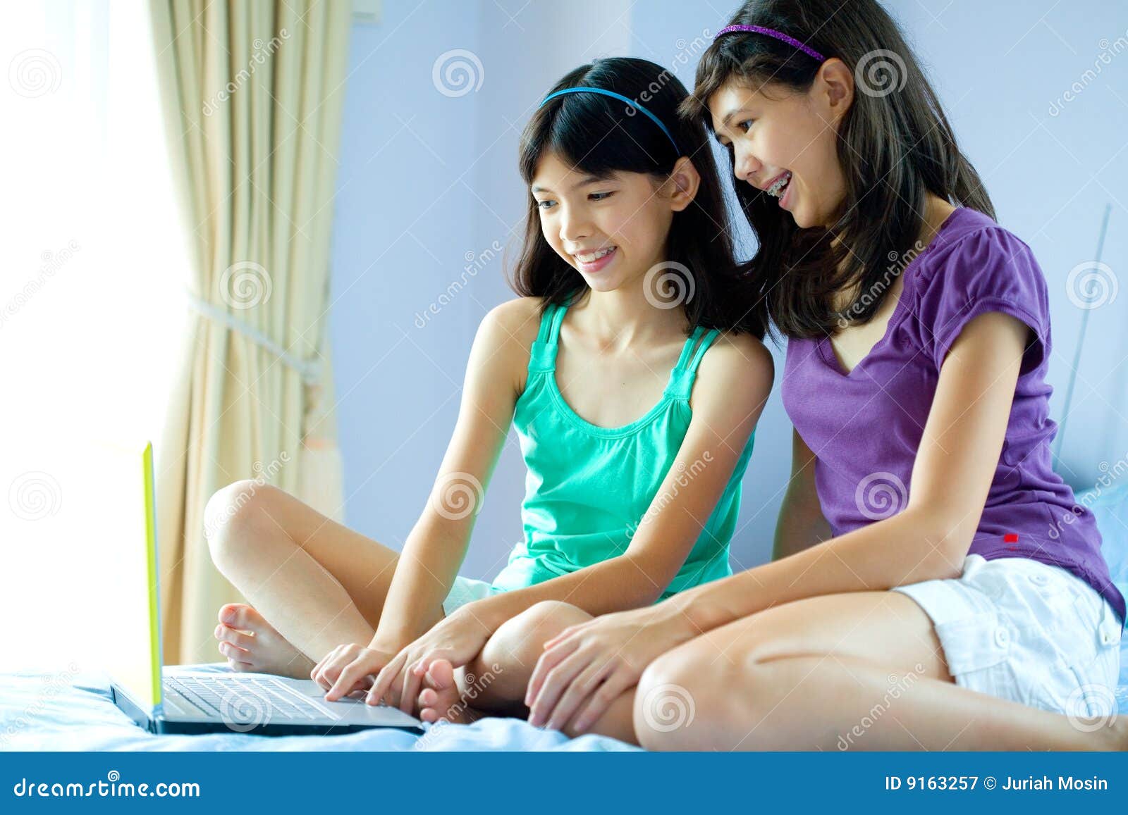 Sisters Sharing A Laptop In Home Environment Royalty Free Stock