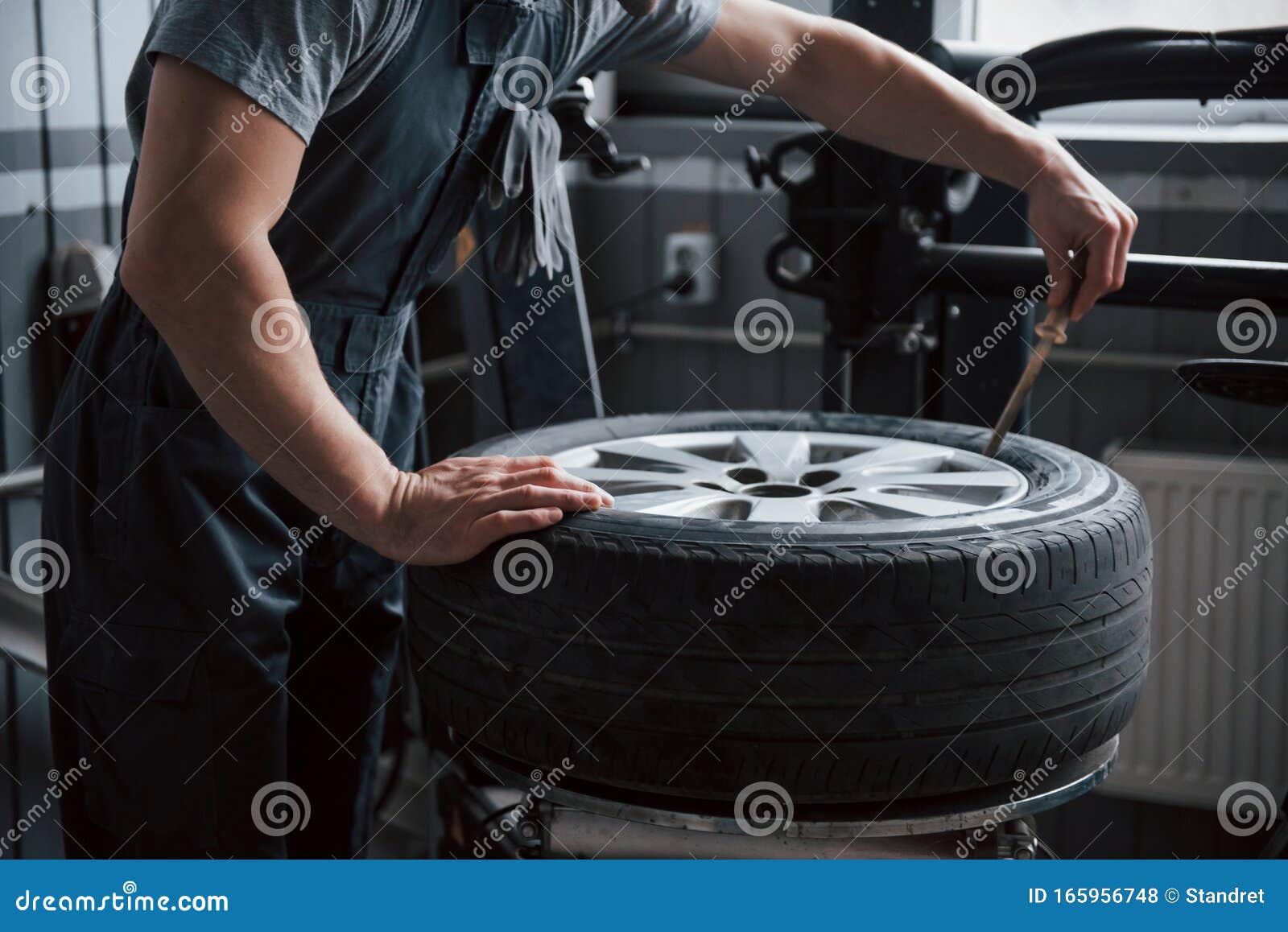 sits perfectly. young man works with wheel`s disks at the workshop at daytime