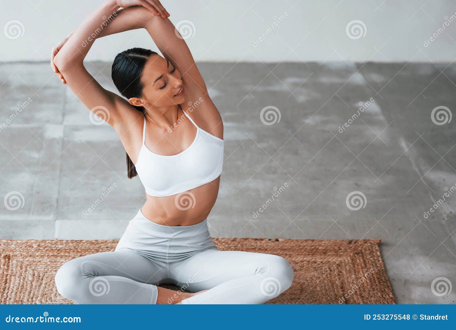 Sits on yoga mat. Woman with sportive slim body type in underwear