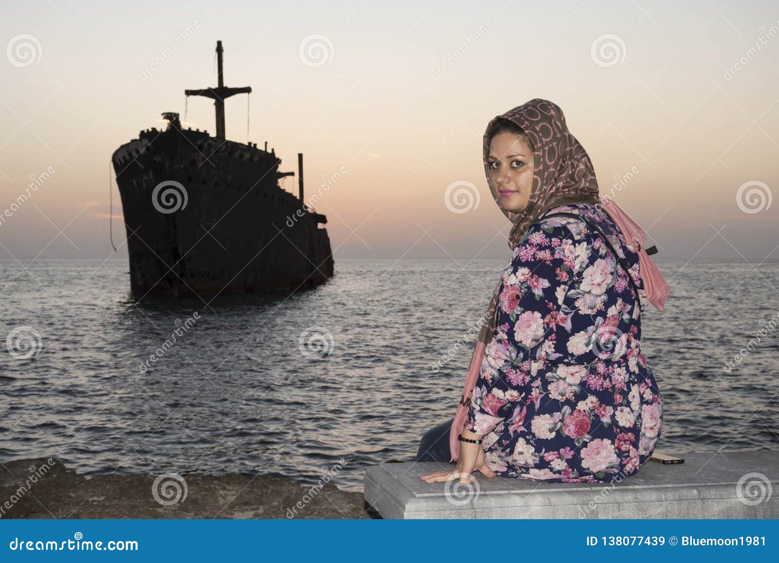 sitting woman with greek ship wreckage in kish island after sunset