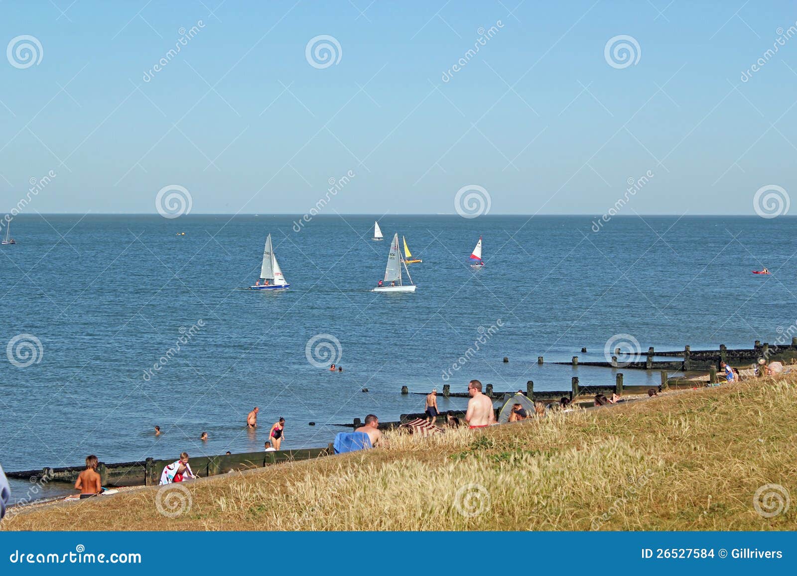 Sjösidagyckel. Detta foto visar folk som 'På/av' tar fördel av en varm sommardag den Herne fjärdkusten, kunde denna bild vara van vid främjar den Herne fjärdstranden och att segla som en sport