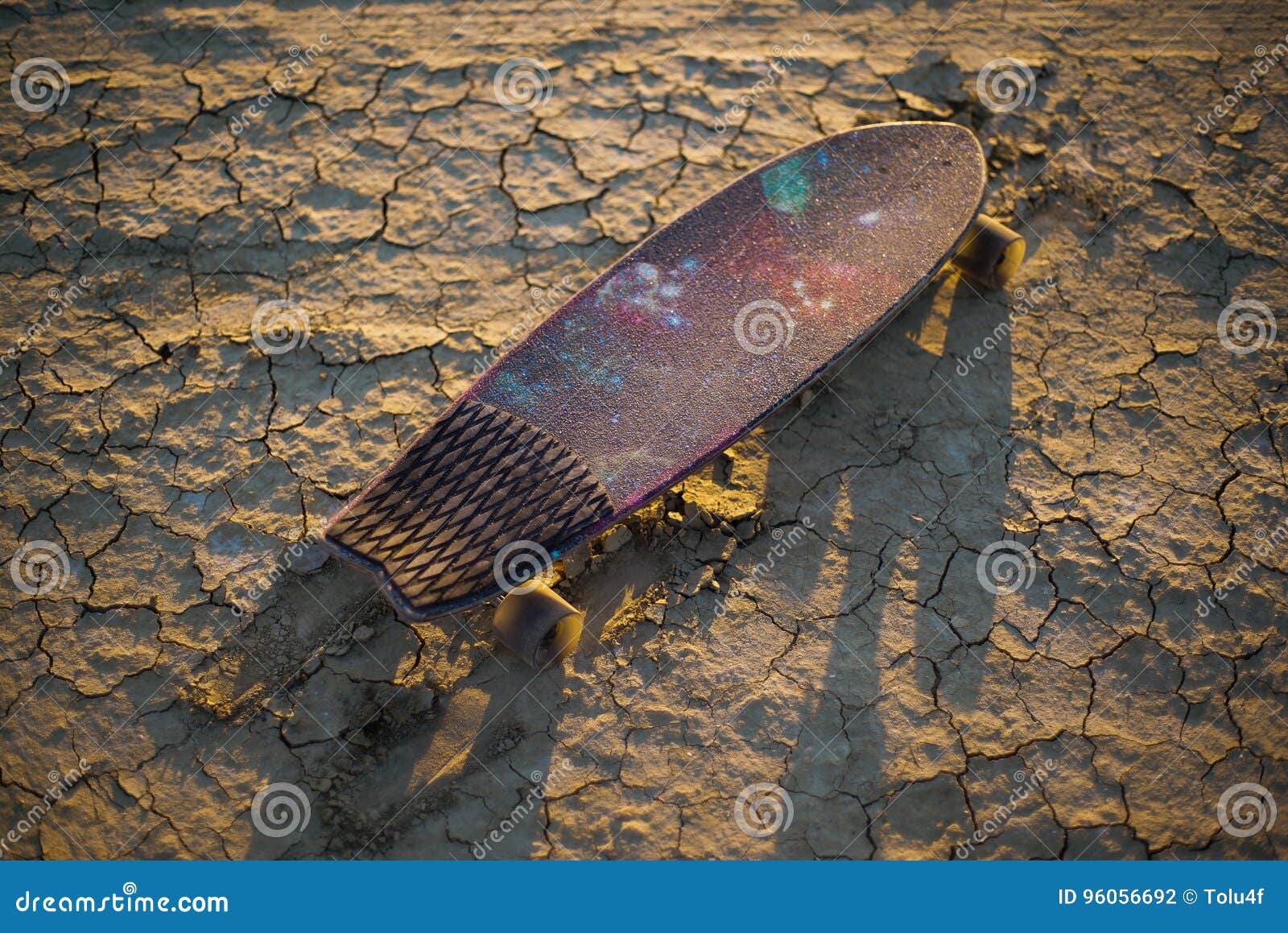 Skateboard or Longboard Stuck in the Sand in the Desert at Sunset Stock