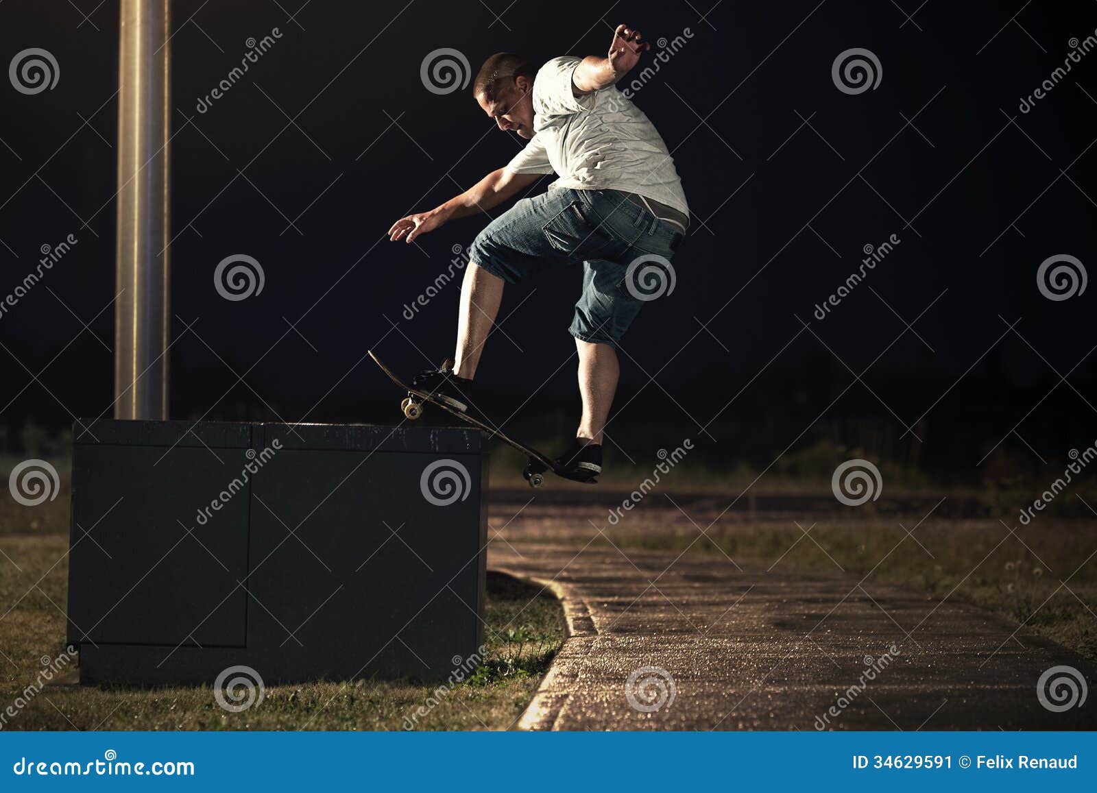 Skateboarder Doing a Frontside Boardslide Trick at Night Stock Image