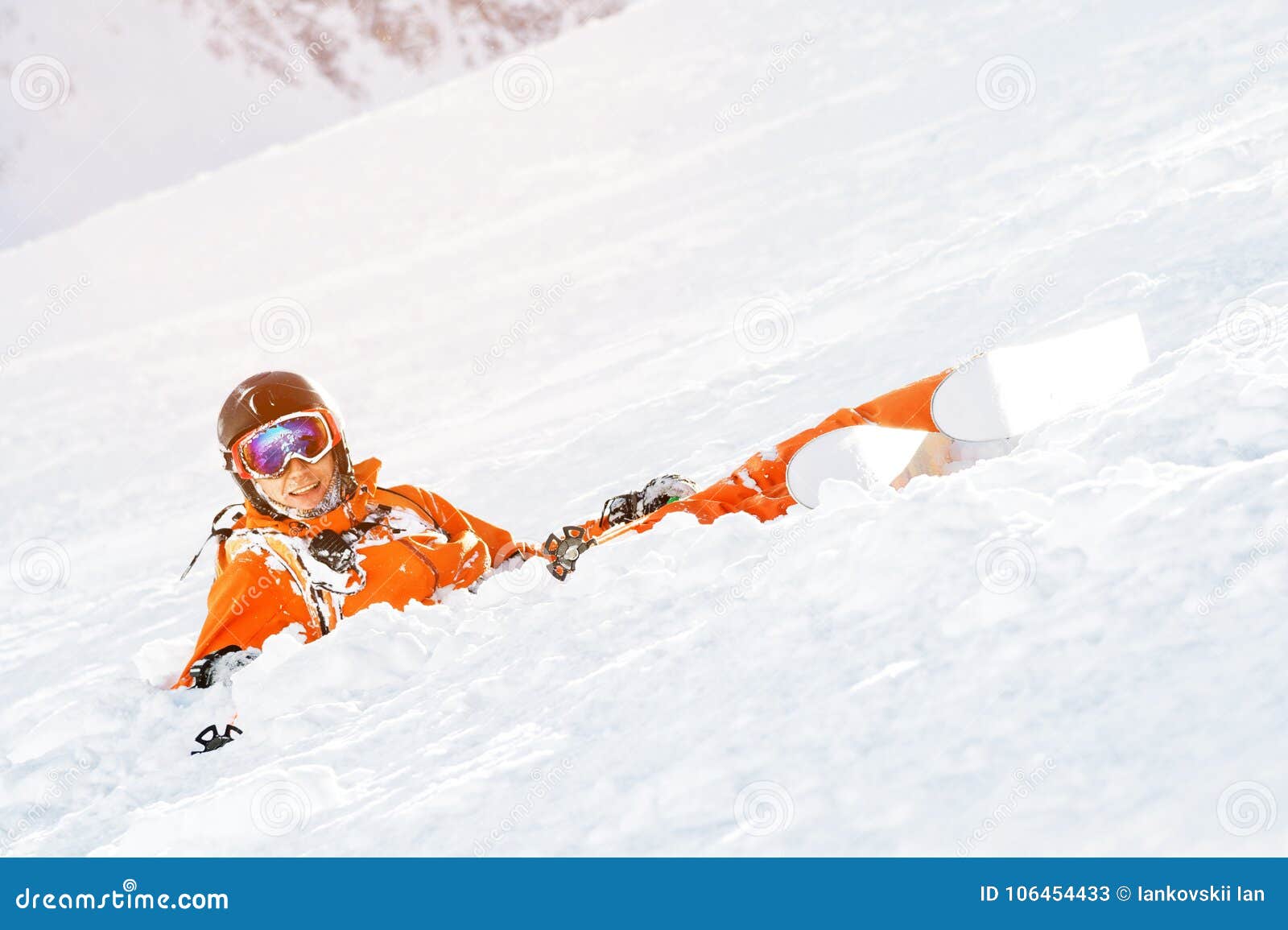 A Skier in an Orange Overall and with a Backpack Lies Happy in the Snow ...