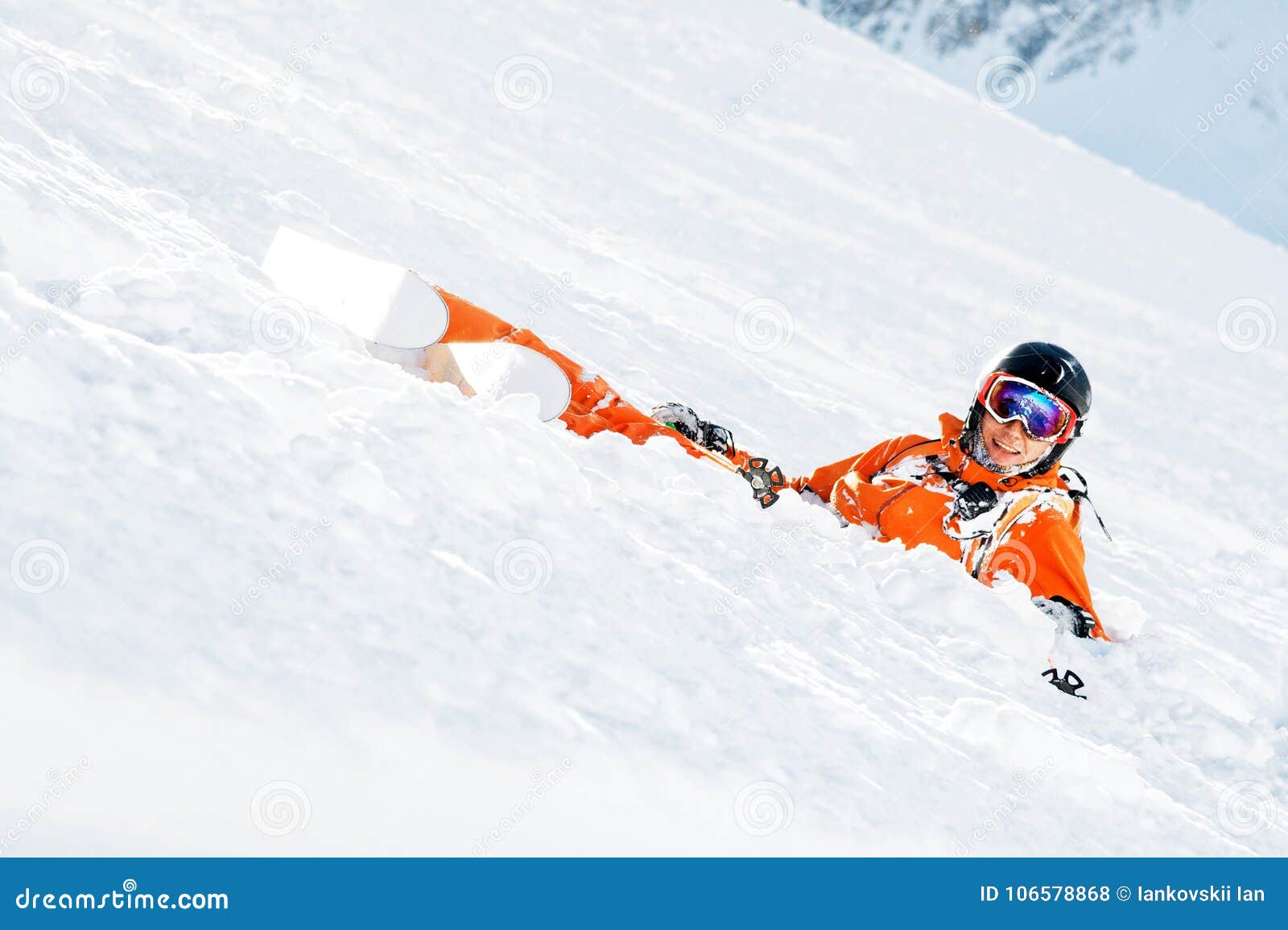 A Skier in an Orange Overall and with a Backpack Lies Happy in the Snow ...