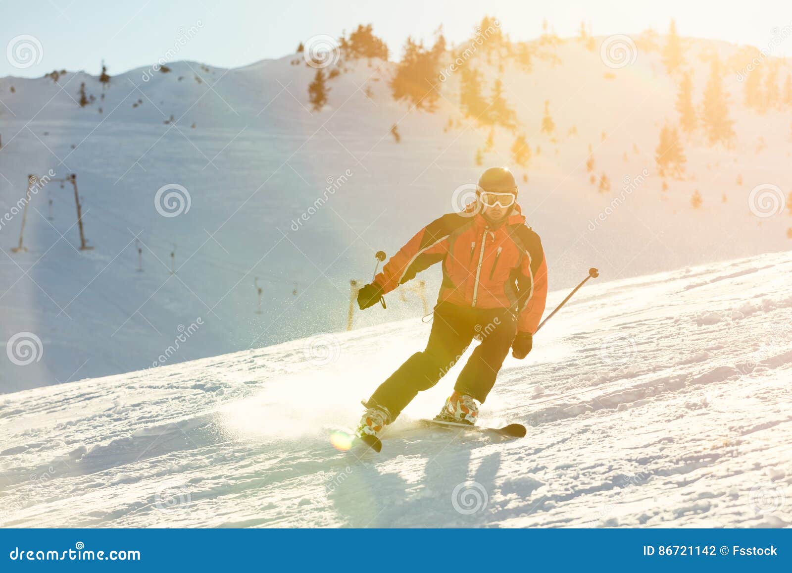 Skier Skiing Downhill in High Mountains Against Sunset Stock Photo