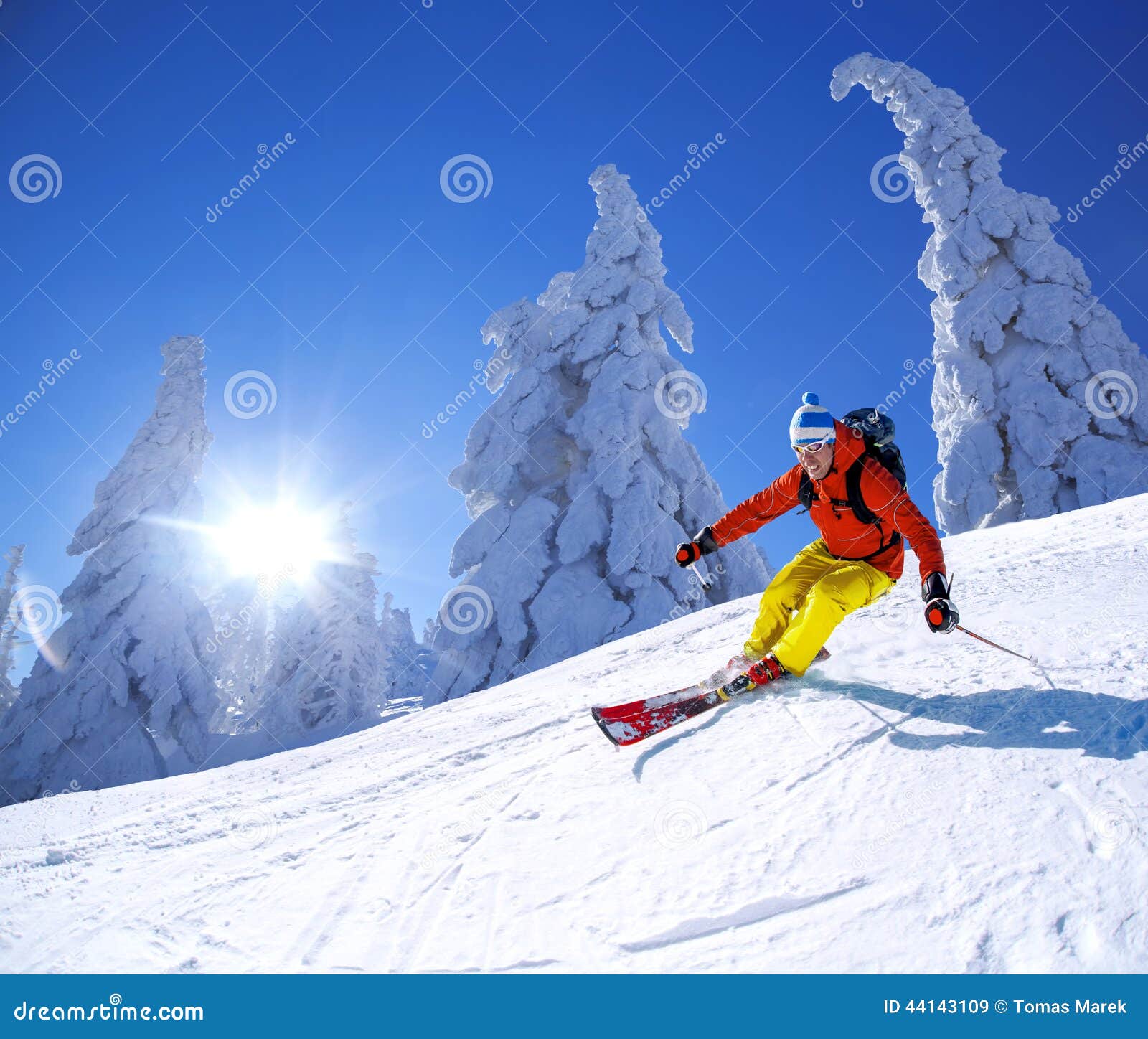 skier skiing downhill in high mountains against sunset