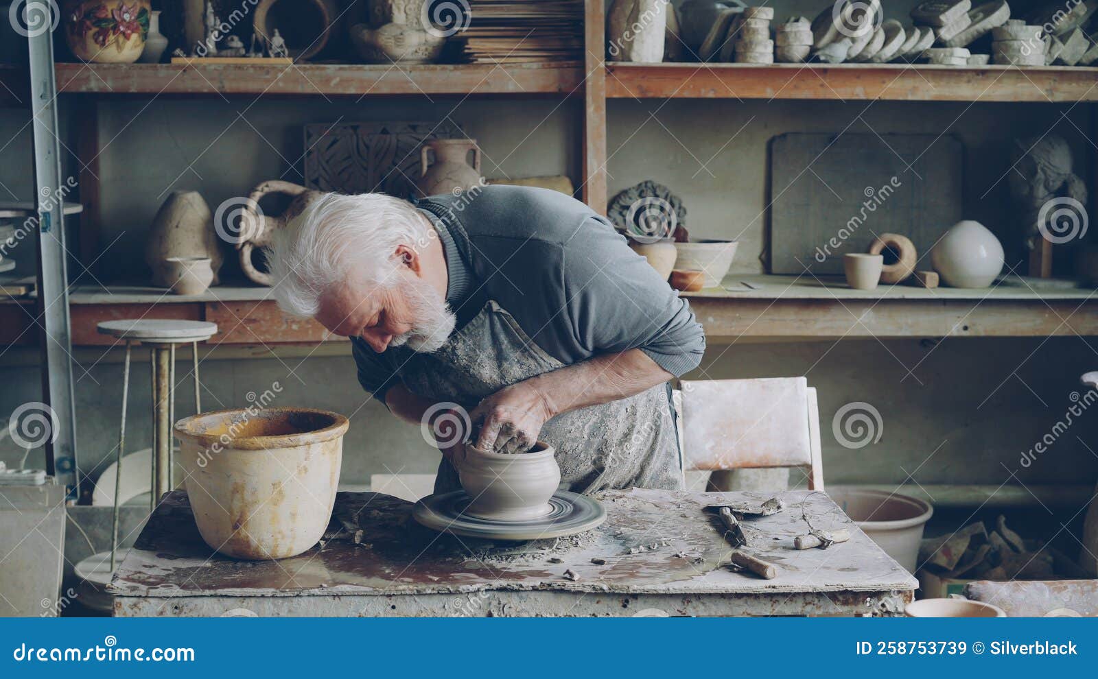 Skilled Elderly Potter is Producing Ceramic Pot on Turning Wheel in