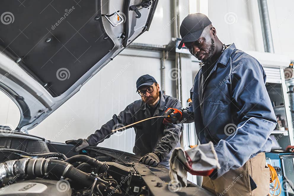 Skilled Mechanics Repairing a Car Engine Using Tools in Modern Auto Repair Shop Stock Photo