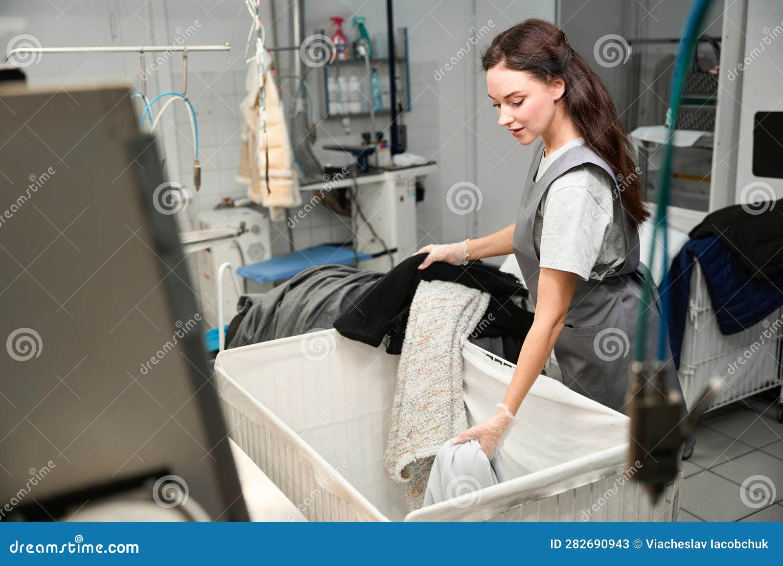 Skilled Woman Laundry Operator Sorting and Inspecting Clothes Stock