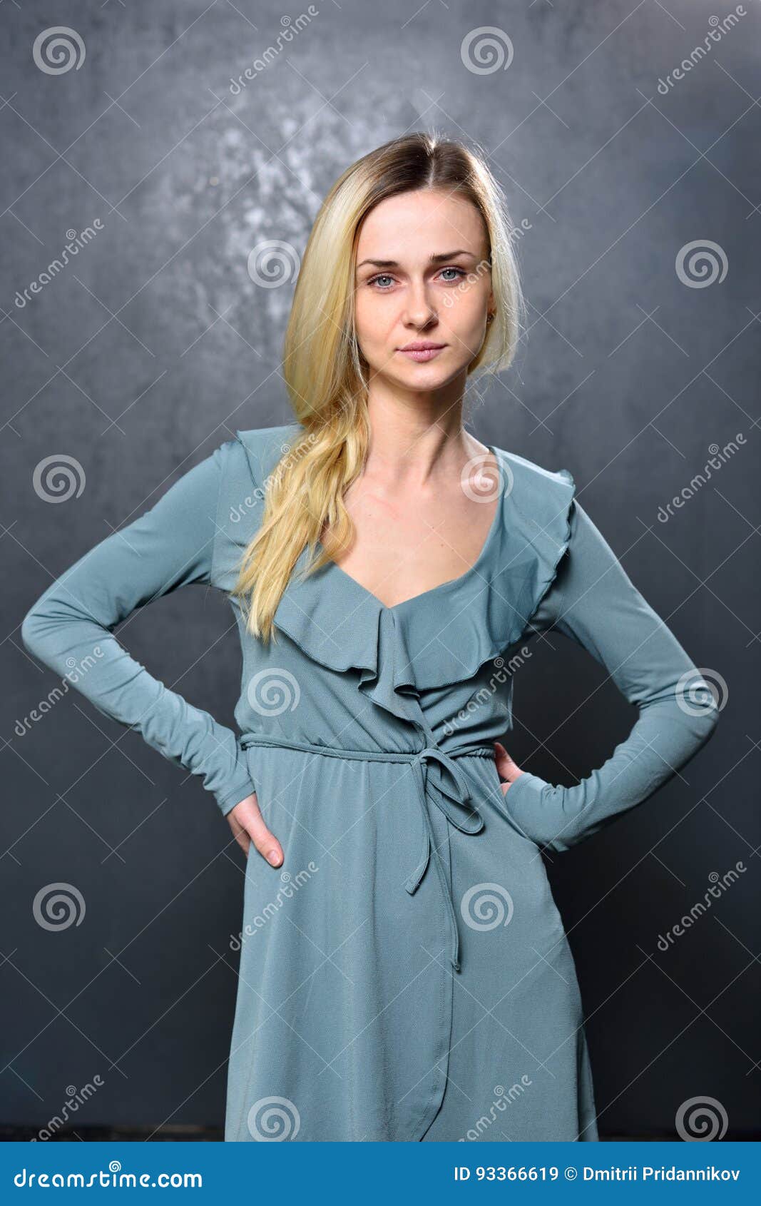 Skinny Blonde Girl In Gray Dress On The Background Of Gray Wall Stock 