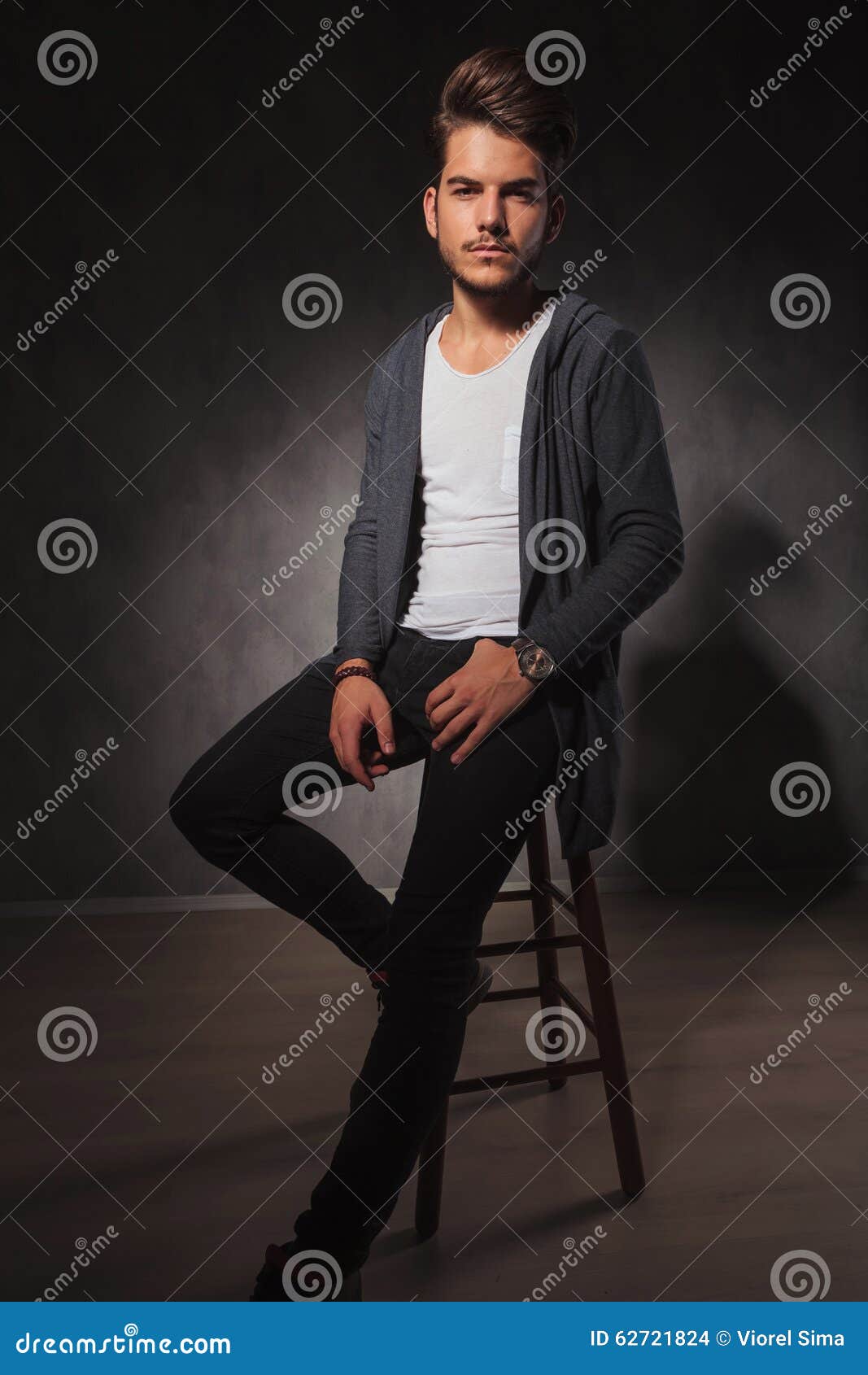 Stylish guy posing in studio sitting on the floor in denim pants and black  sweatshirt. Male student portrait full on white backg Stock Photo - Alamy