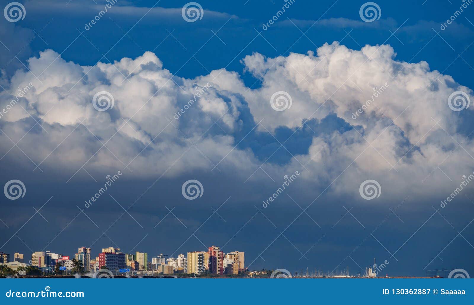 skyscrappers near sea with stormy clouds as hat