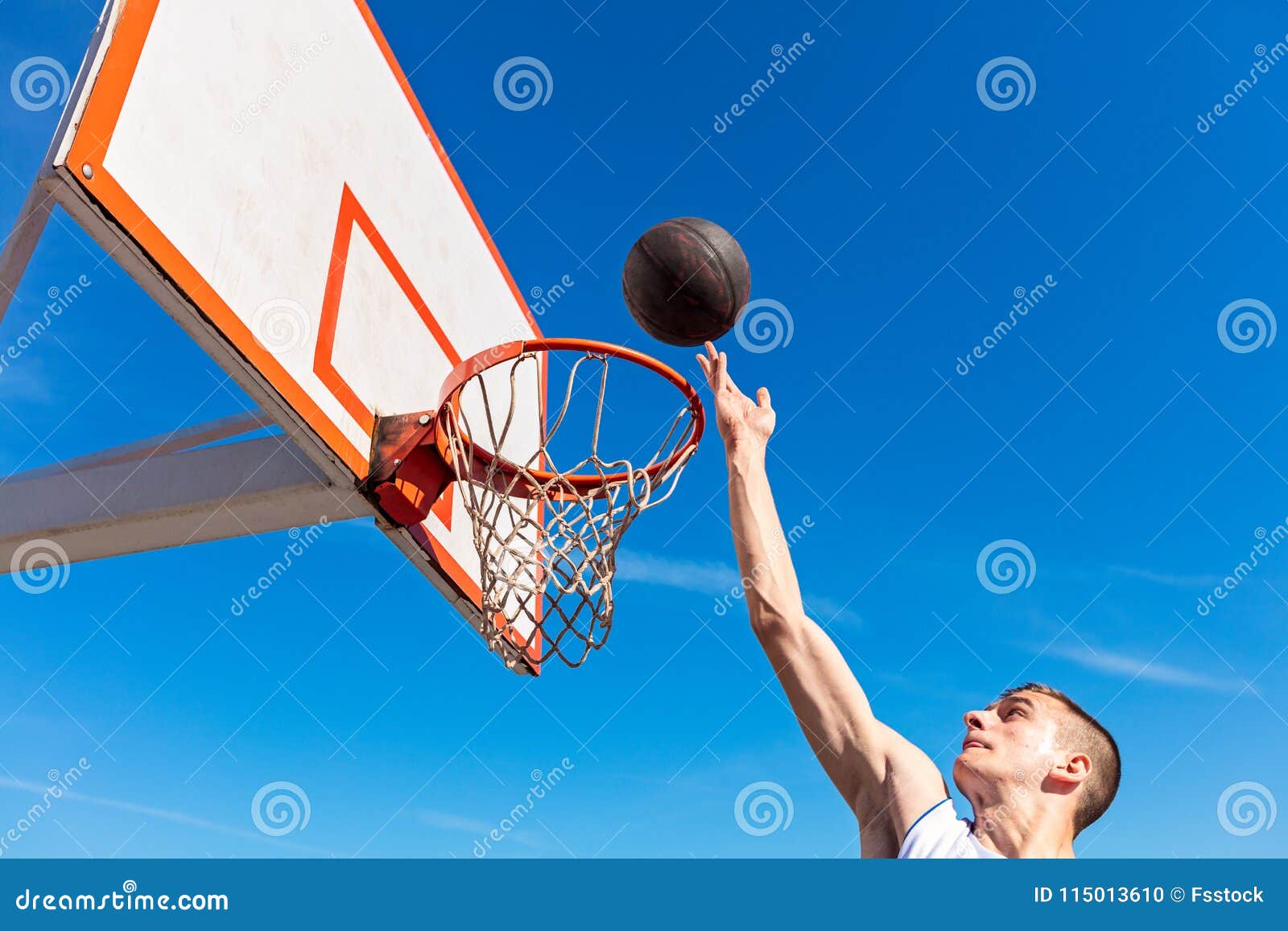 Slam Dunk. Side View of Young Basketball Player Making Slam Dunk Stock