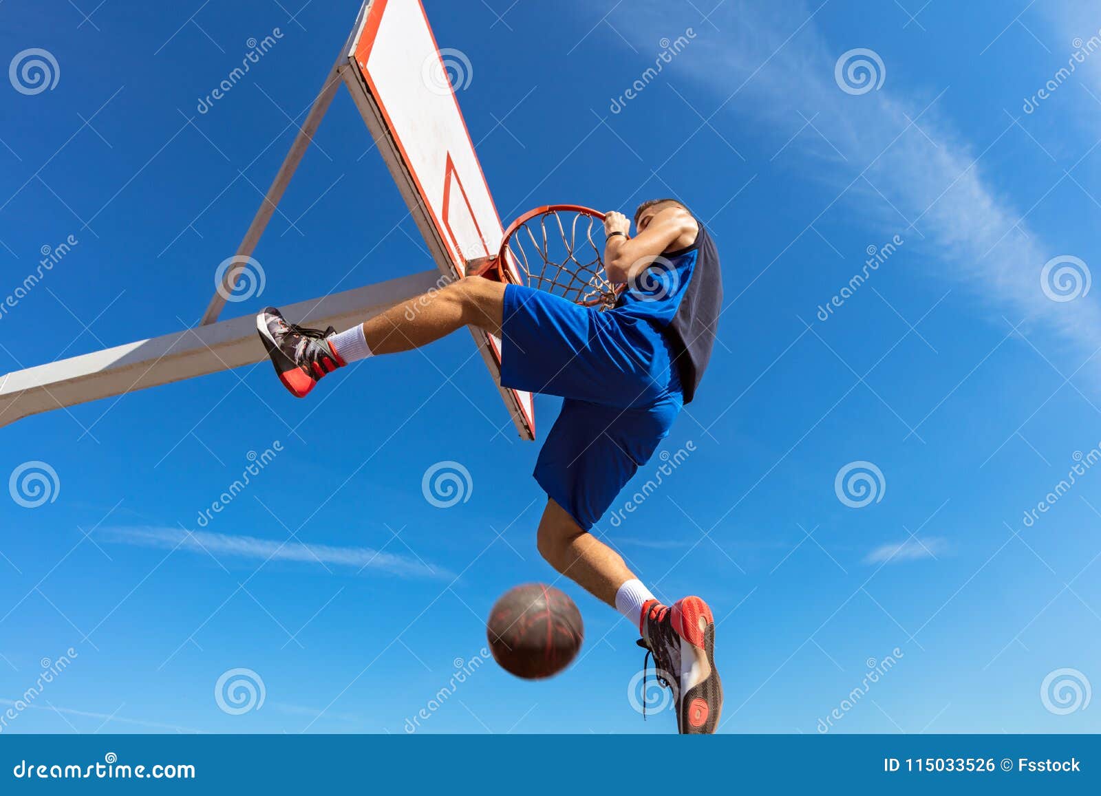 Slam Dunk. Side View of Young Basketball Player Making Slam Dunk Stock