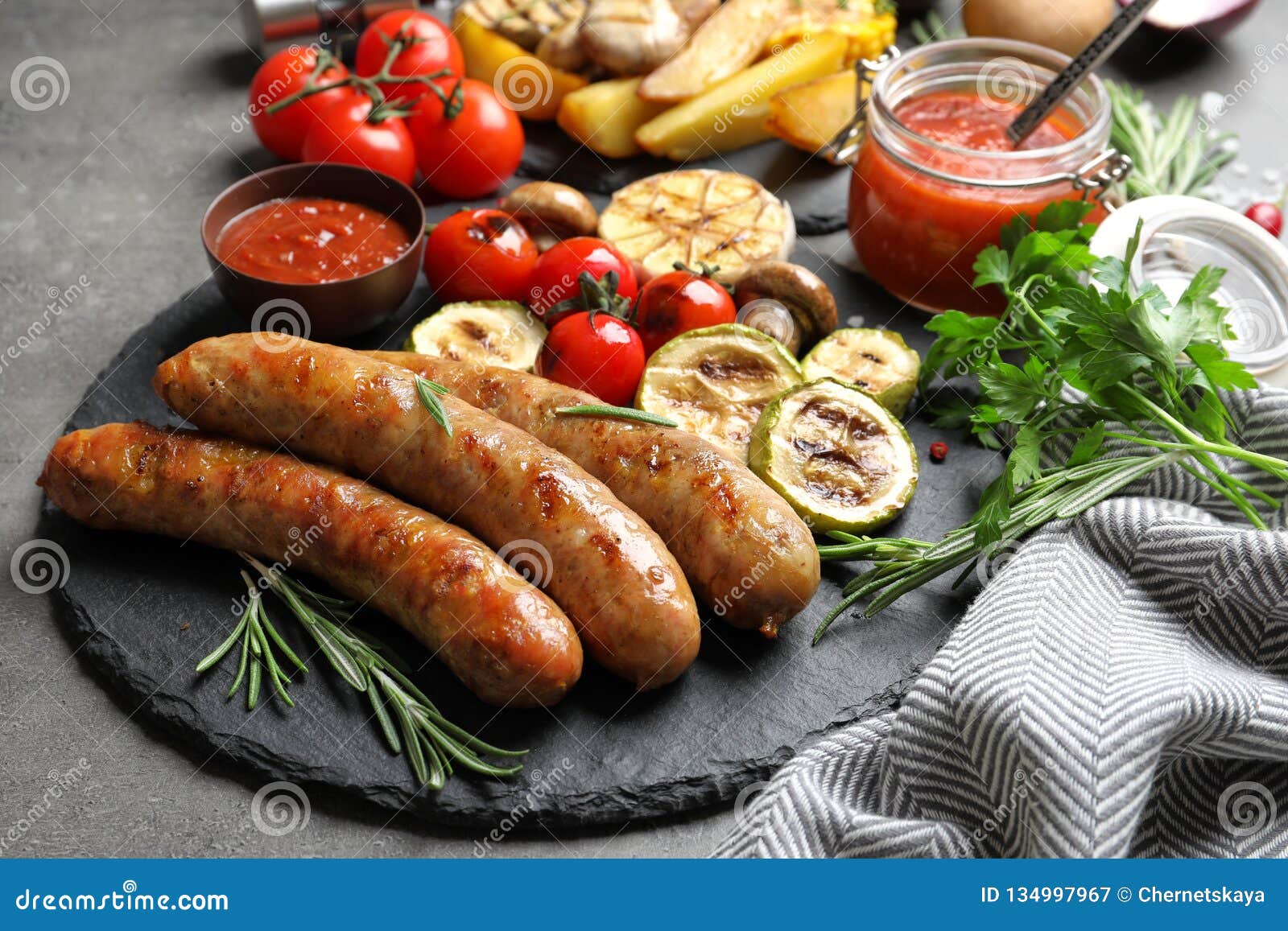 slate plate with delicious sausages and vegetables served for barbecue party