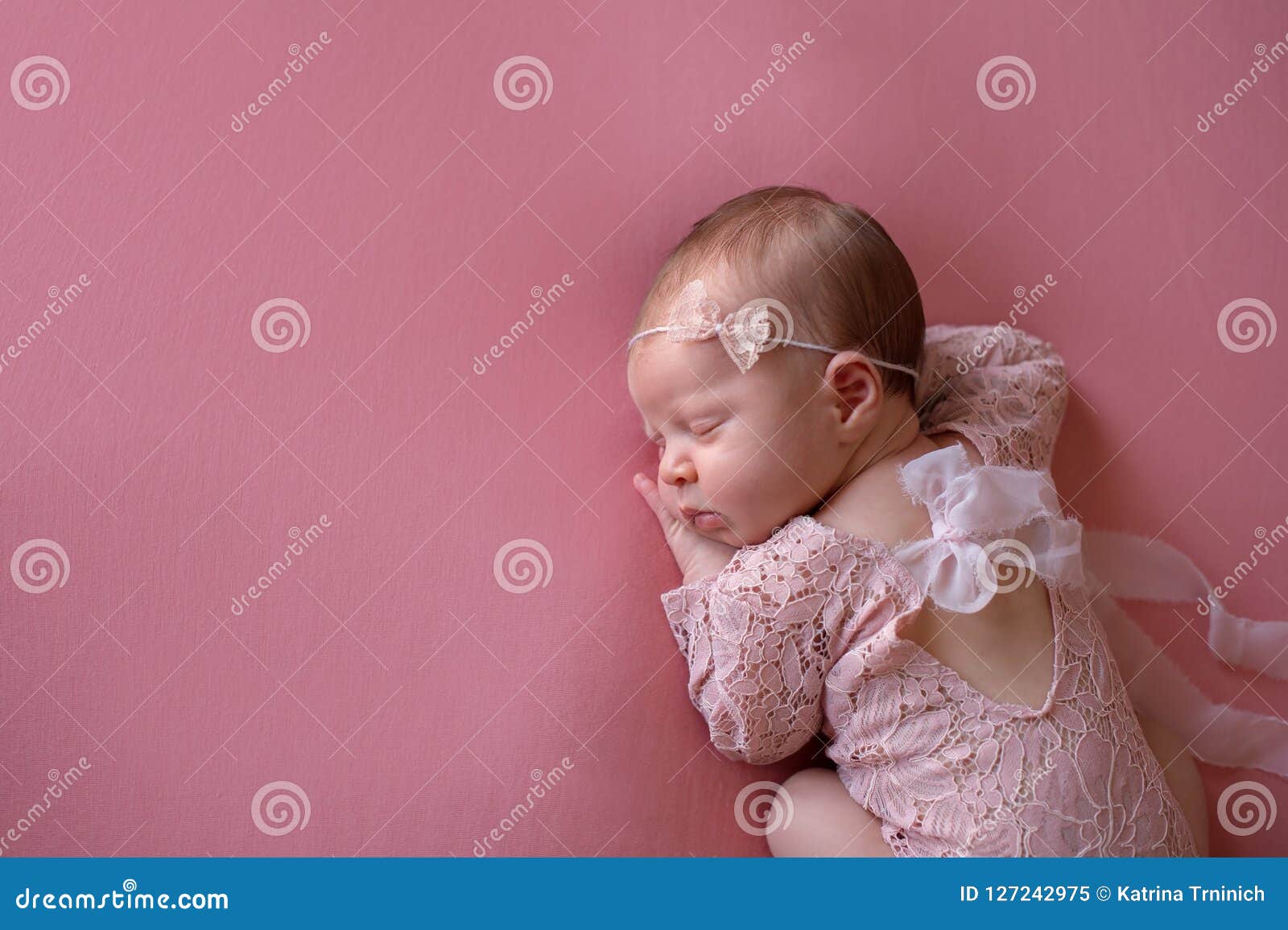 sleeping newborn baby girl wearing a pink lace romper