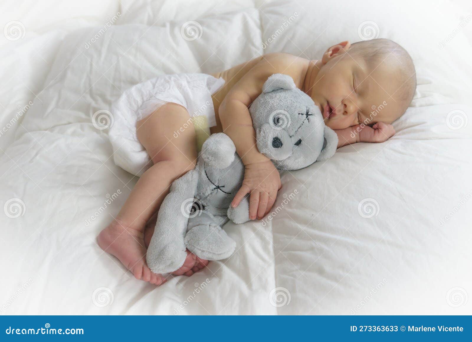 sleeping newborn baby hugging a teddy bear