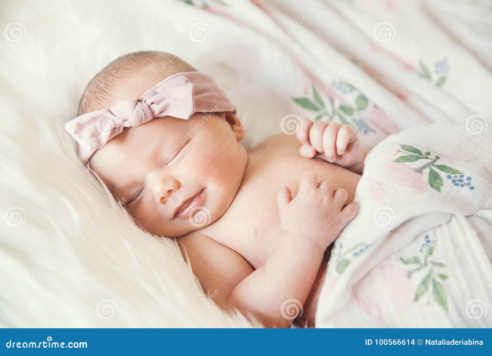 Sleeping Smiling Newborn Baby In A Wrap On White Blanket 