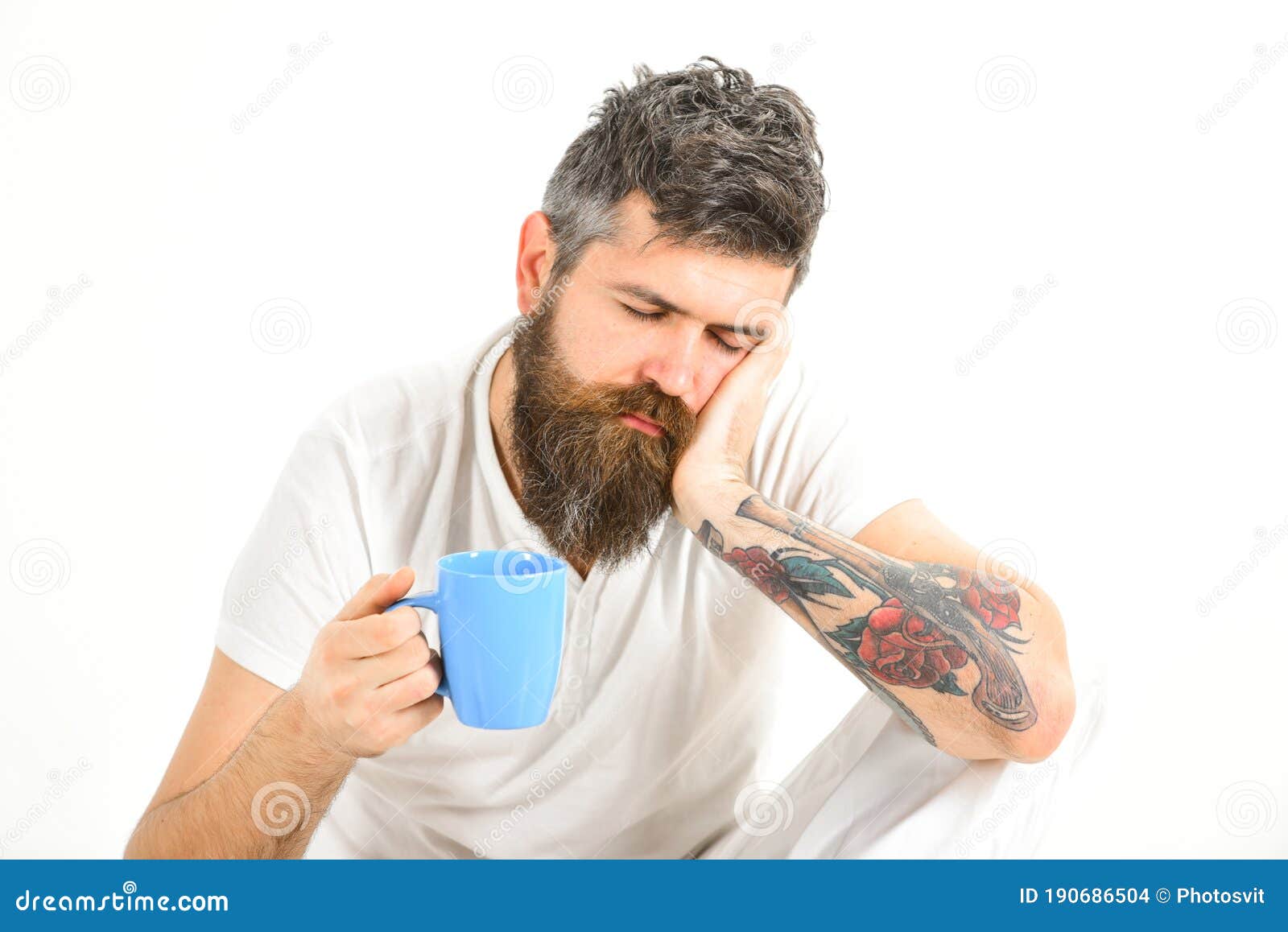 sleepy hipster with beard and mustache holds mug in hand.