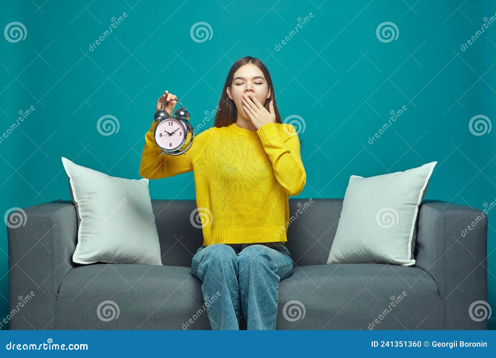 Sleepy Young Girl Yawn Covering Mouth By Hand Holding Alarm Clock